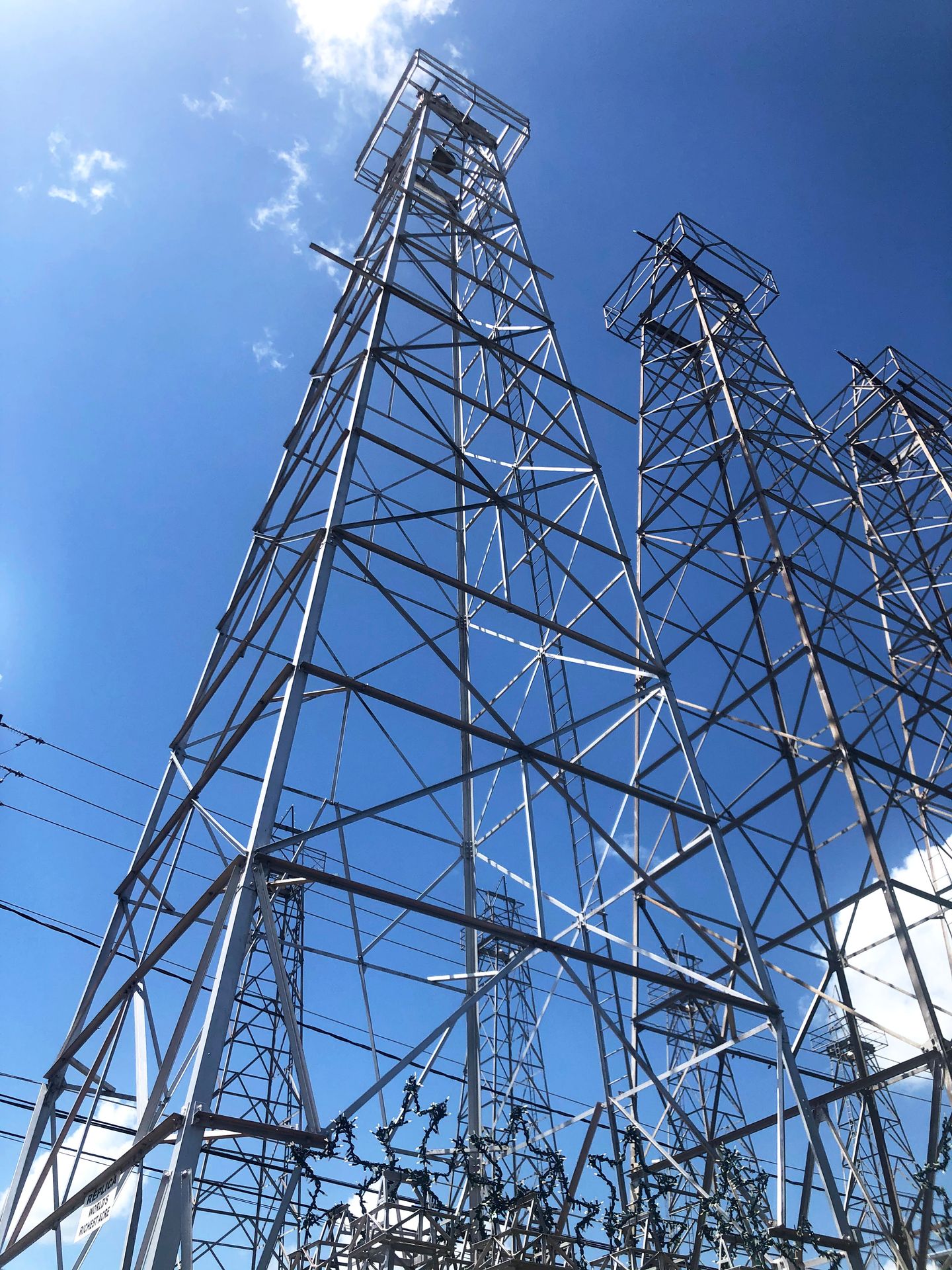 3 very tall metal oil derricks.
