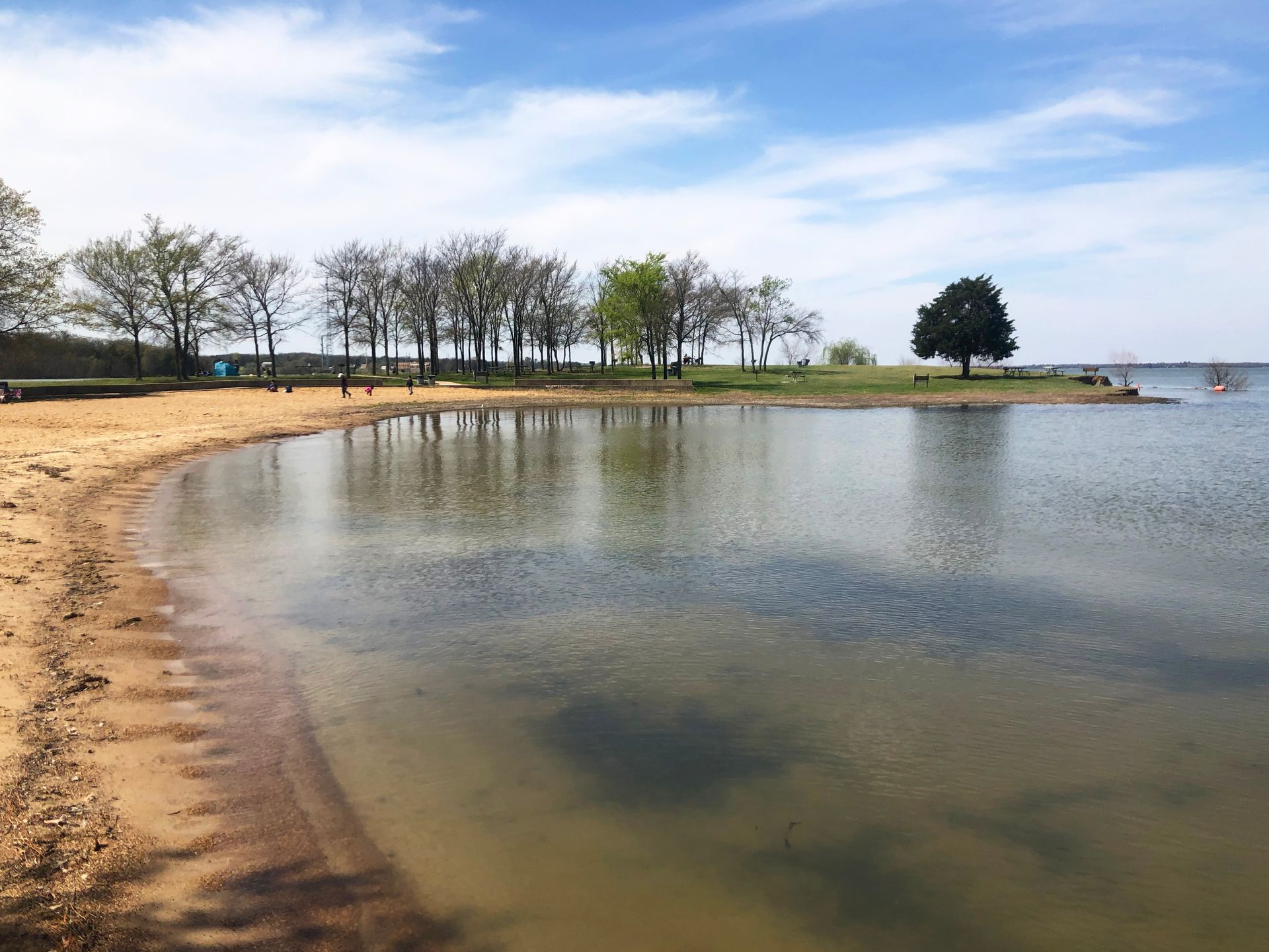 A lake with a small beach area and some trees in the distance.