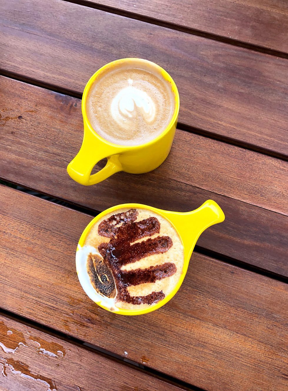 Two yellow mugs with latte art from La La Land Kind Cafe.