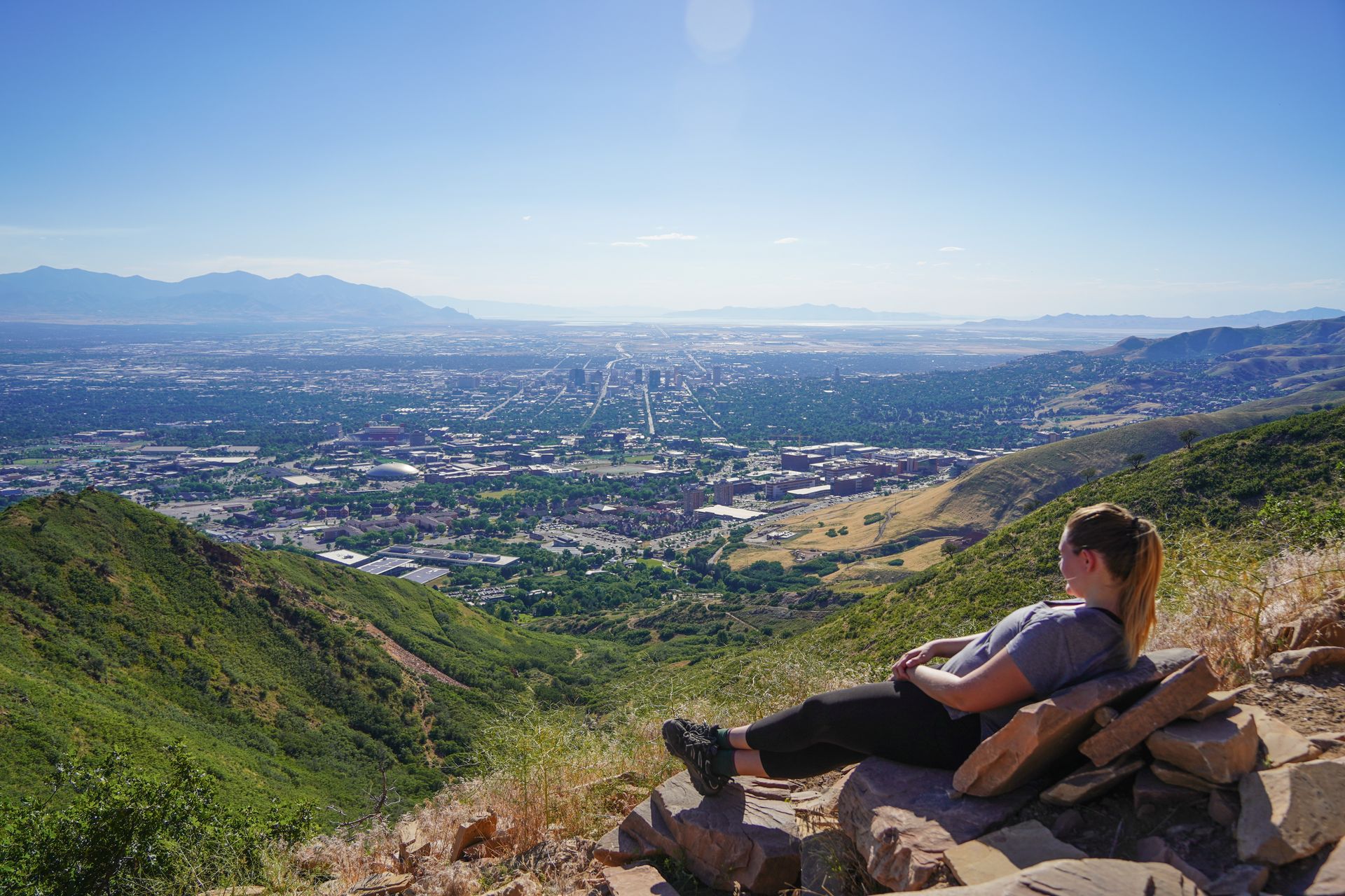 Lydia laying back on some rocks that resemble a couch with a view of the city below.