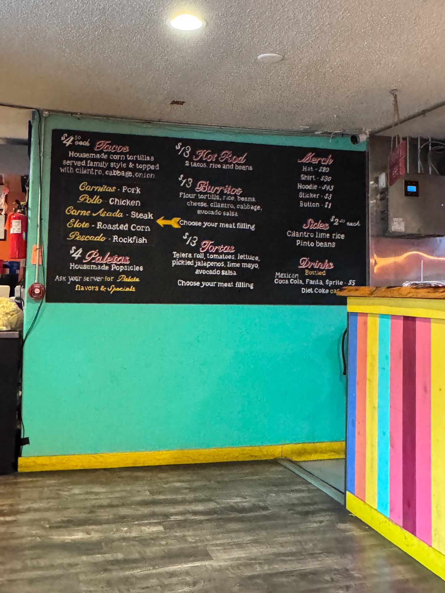 The menu and colorful walls at one Chicharron Taqueria