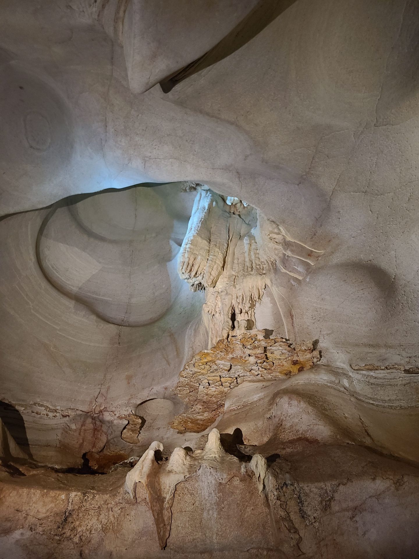 The interior of Longhorn Caverns. There are smooth white walls and cave formations hanging from the ceiling.