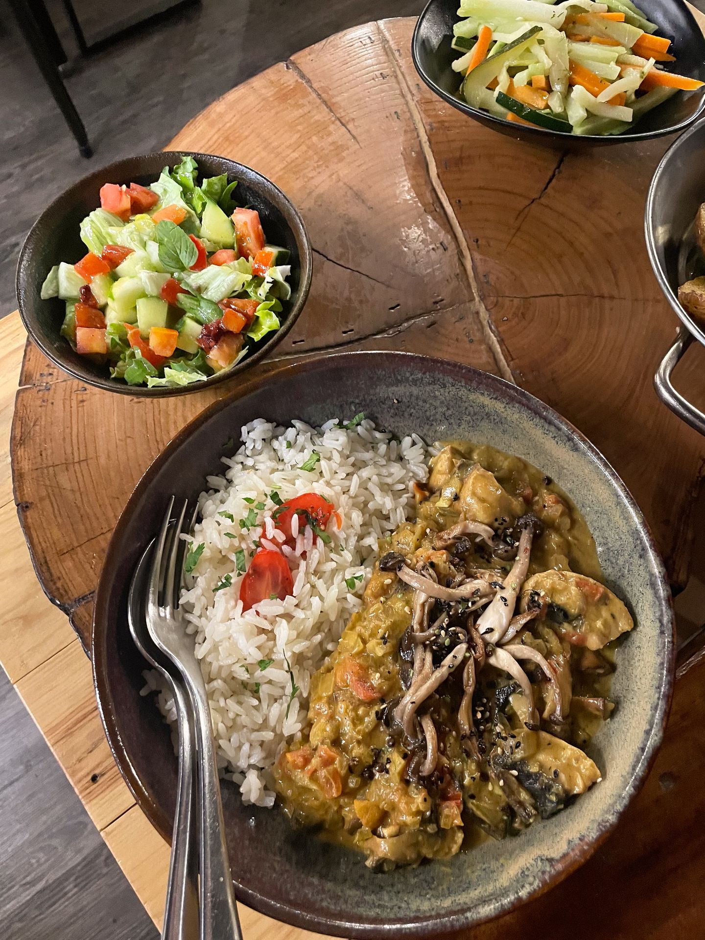 A plate of mushroom curry and rice next to a salad at MadMarket