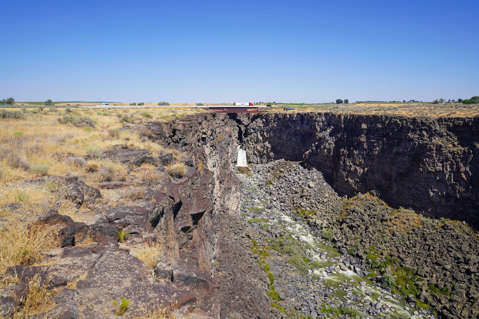 A rocky canyon with a waterfall in the distance.