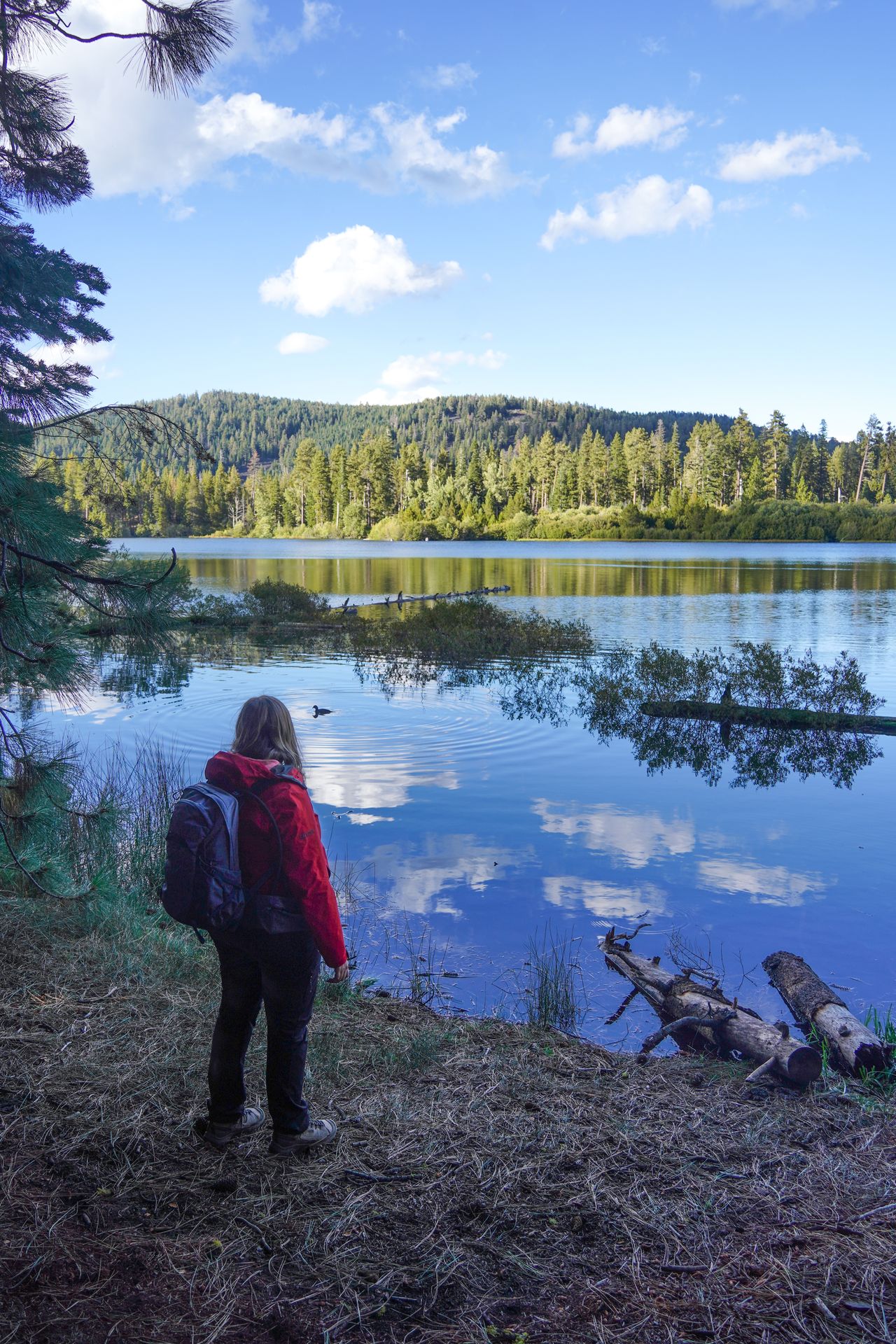Lydia standing next to Manzanita Lake, as the lake reflects the sky