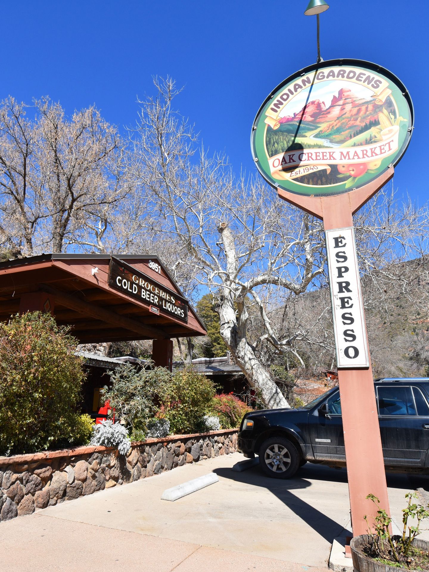 A tall sign that reads "Indian Gardens Oak Creek Market" with the word espresso written vertically. The entrance of the market is in the background.
