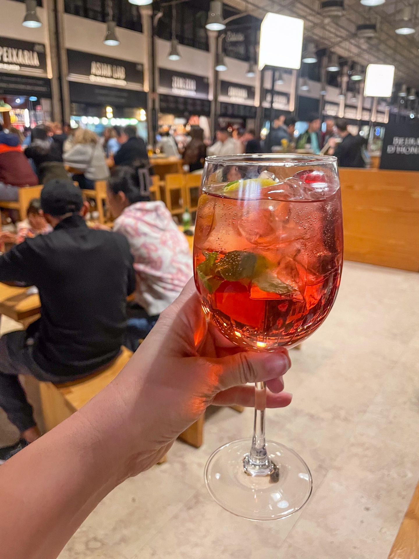 Holding up a port wine inside of Time Out Market Lisboa