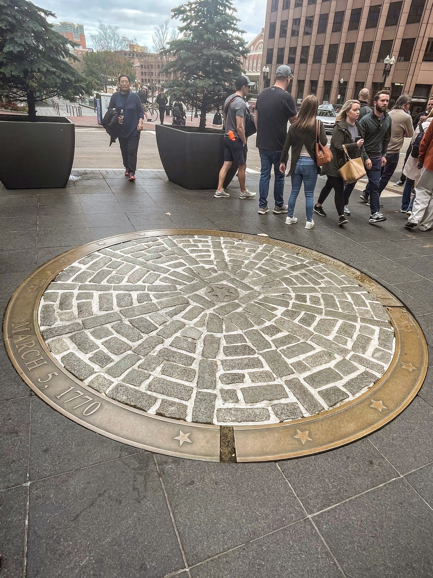 A large plague on the ground representing the place where the Boston Massacre occurred. The site is round and features bricks with a gold rim.