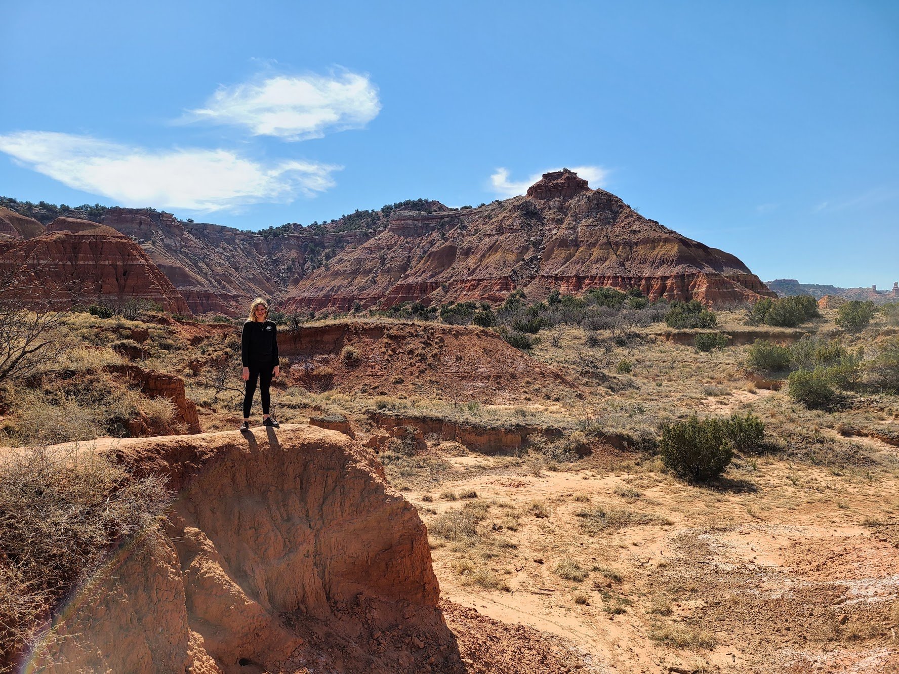Lydia standing on an orange rock face with an orange rock formation in the background.
