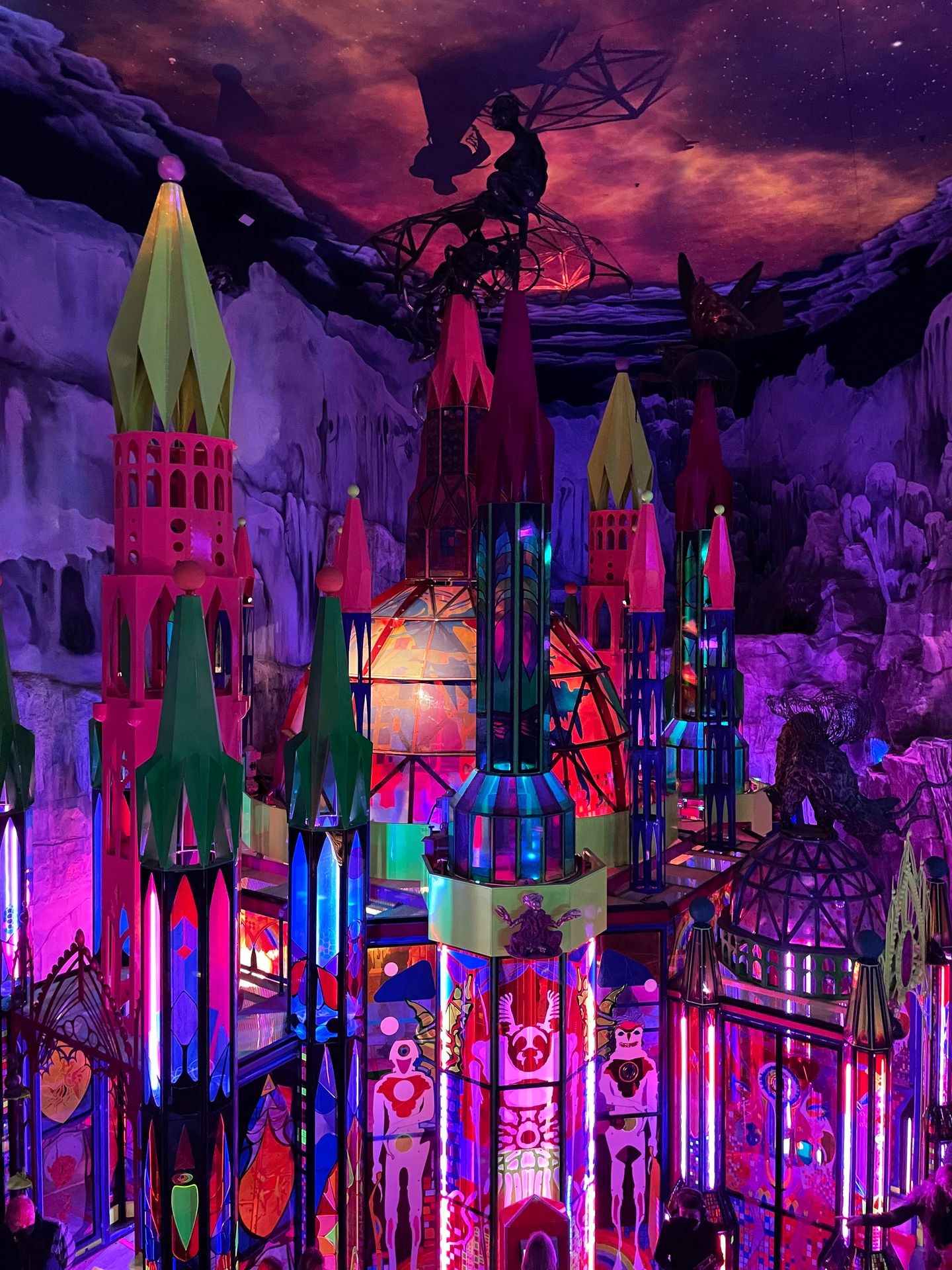 A castle-like building inside of Meow Wolf. The room is mostly pink with a cloudy pink sky above.