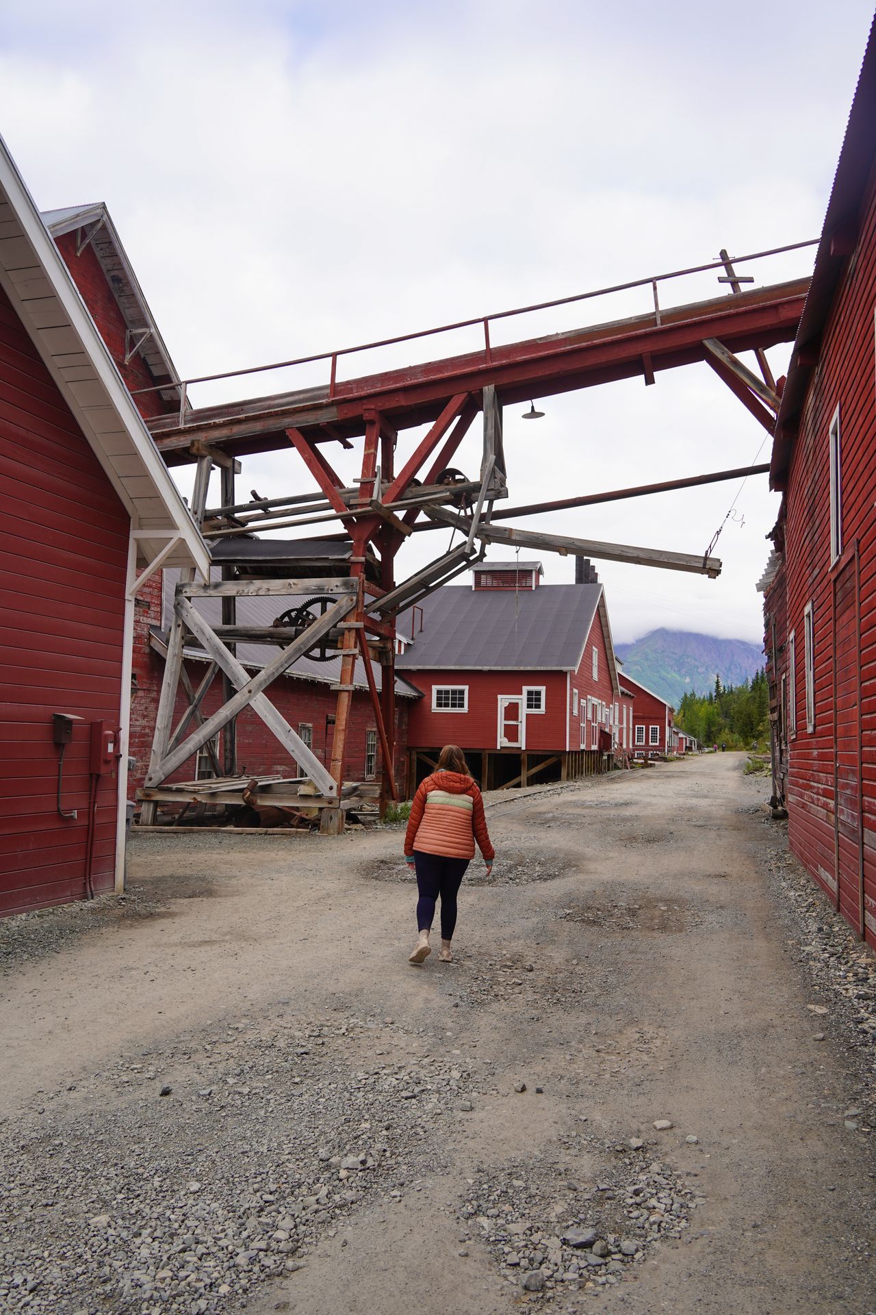 Lydia walking next to the red buildings of the Kennecott Mill
