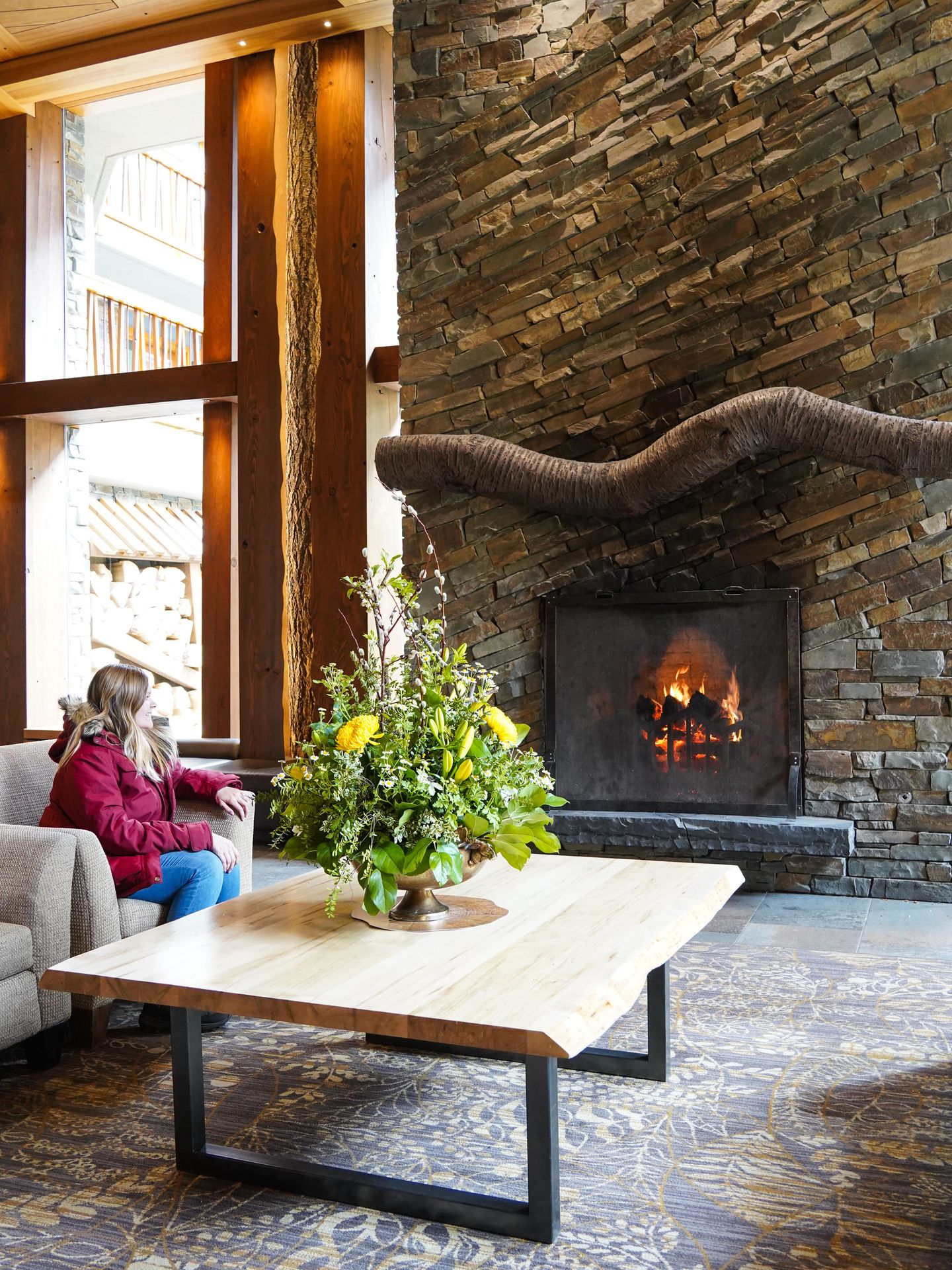 Lydia sitting on a couch next to a fireplace inside of the lobby of the Moose Hotel.
