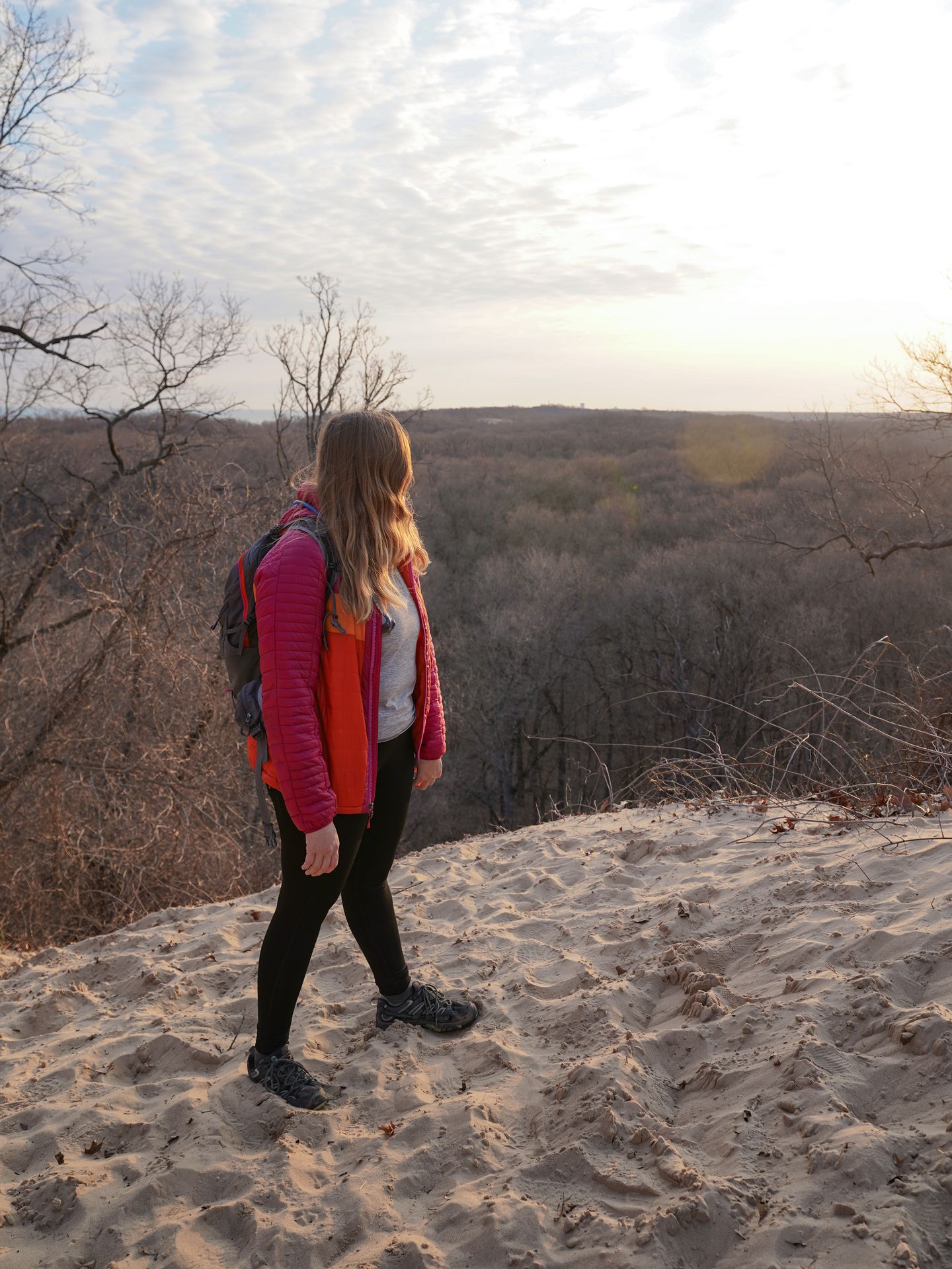 Lydia standing at the top of Mount Jackson, there are trees in the distance