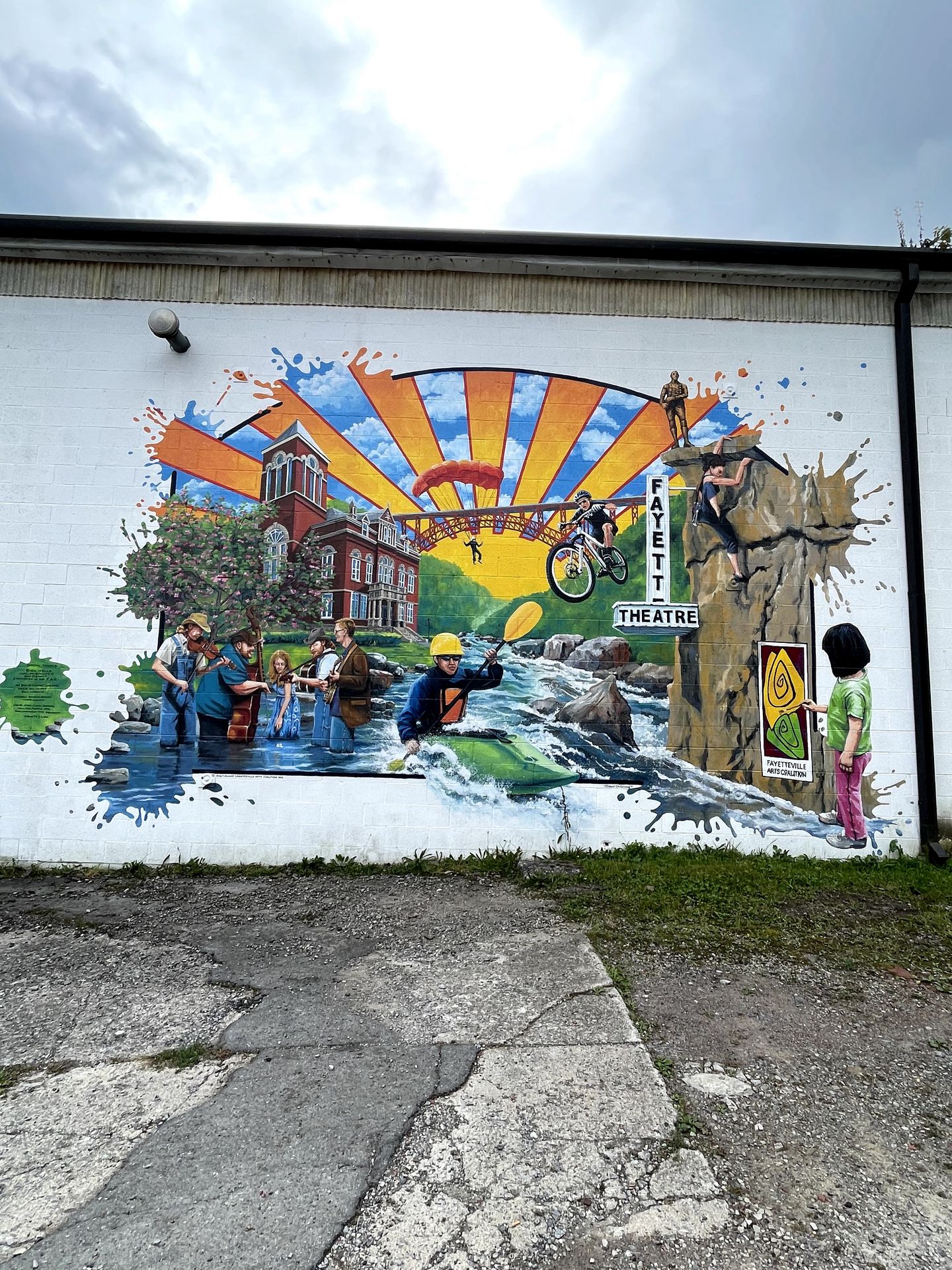 A colorufl mural that includes someone kayaking on a river, a biker, a rock climber, people playing music while standing in a river and someone parachuting from the New River Gorge Bridge.