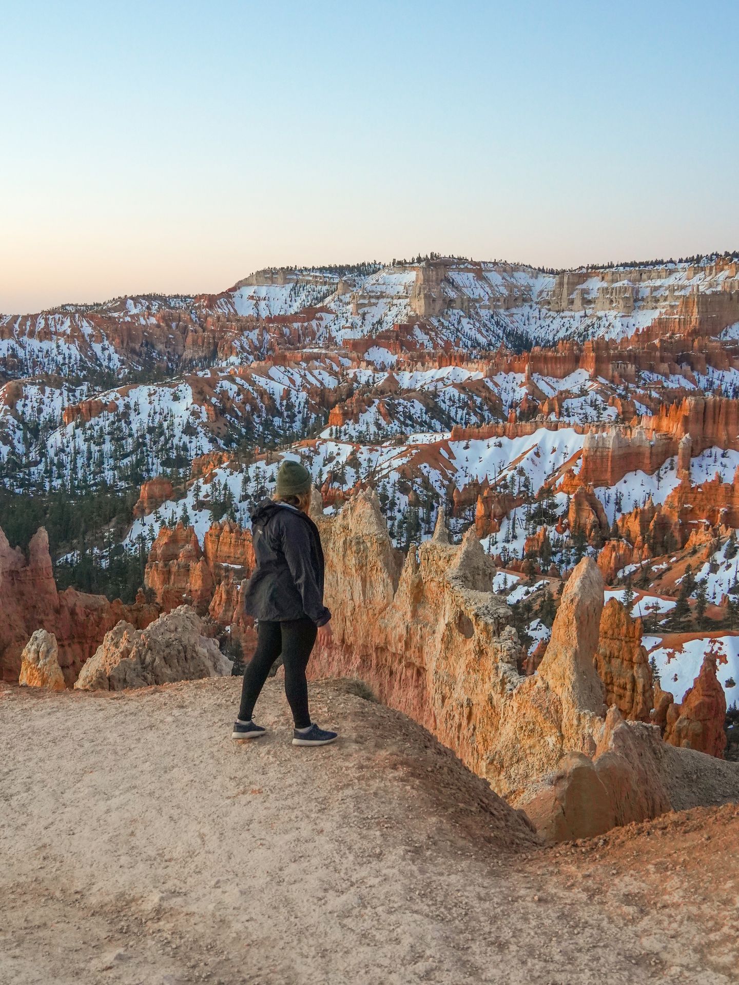 Lydia looking out at snow-covered hoodoos at sunrise at the start of the Navajo Loop trail