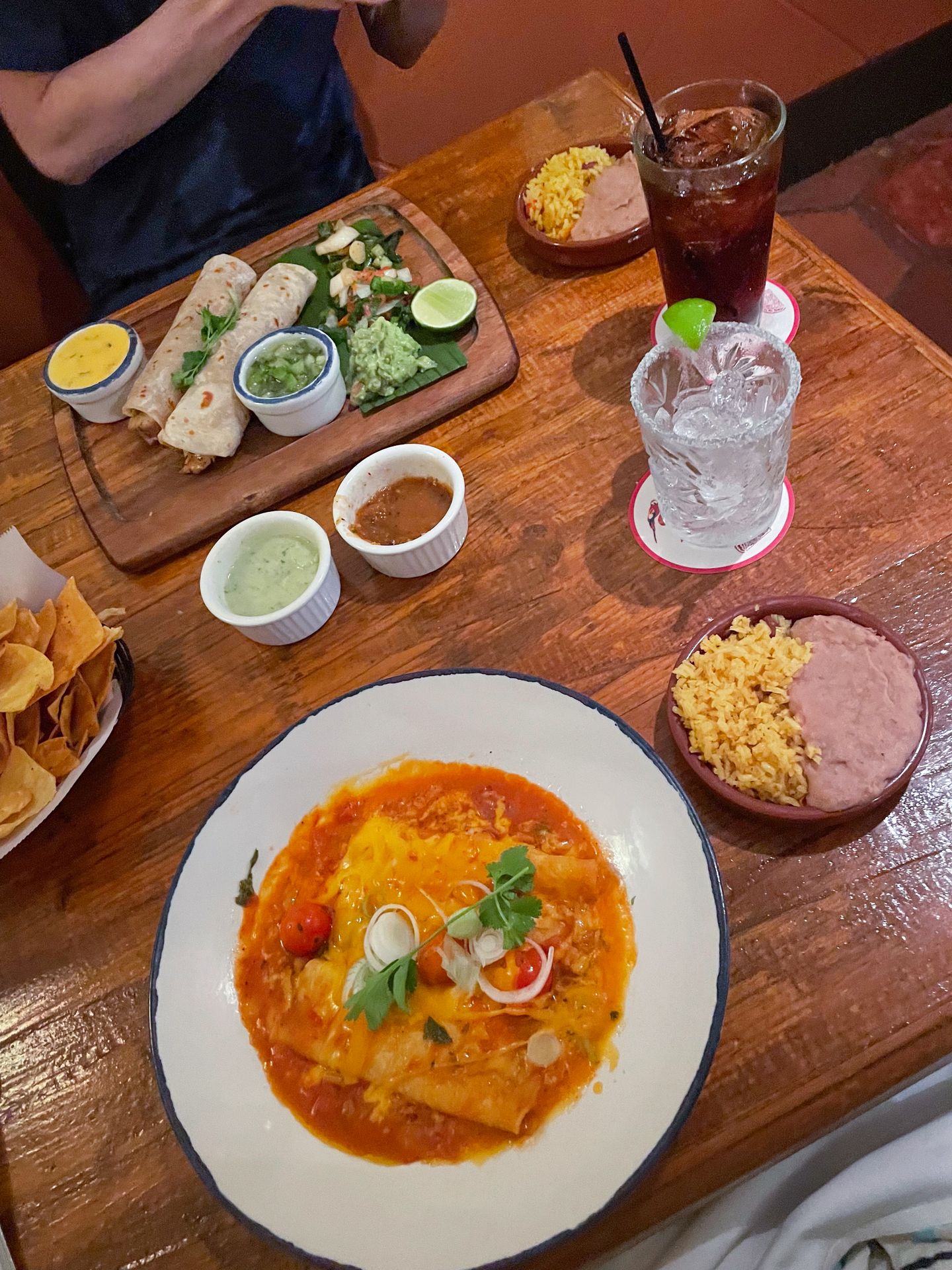 Two meals at Ninfa's. The closest meal is enchiladas with a red sauce.