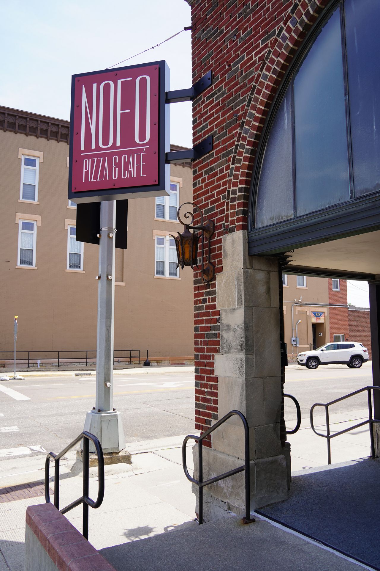 The exterior of NoFo Pizza, which is a brick building with an arch entrance