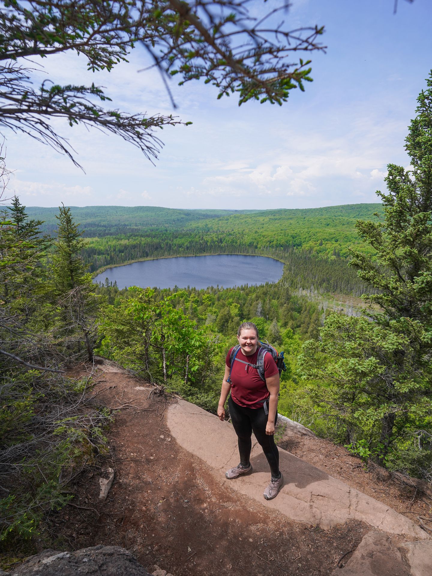 Lydia standing with a view of a small, round lake (Oberg Lake) behind her.