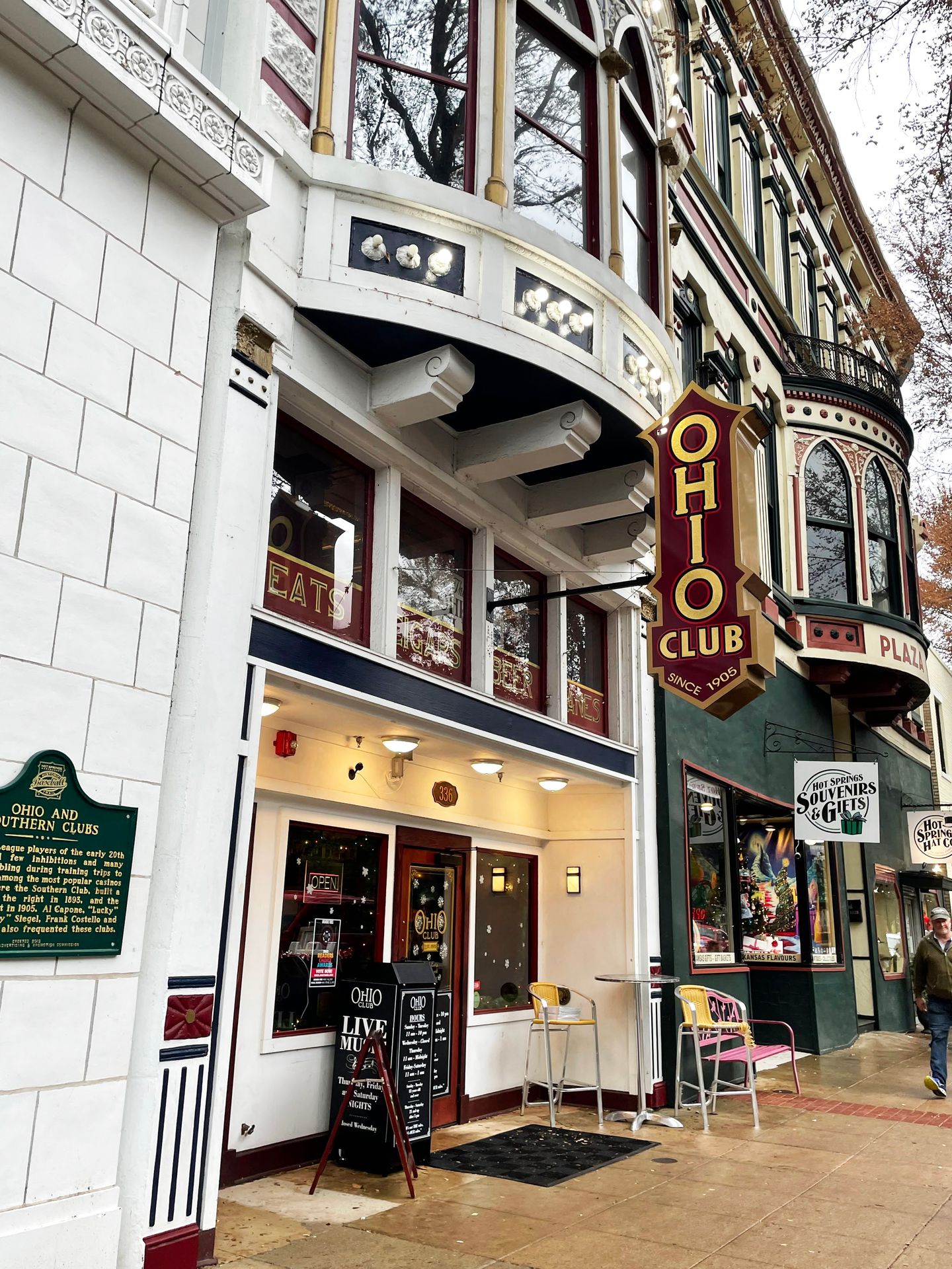 The exterior of The Ohio Club. The building is white and has a red and yellow sign extending out of from the building.