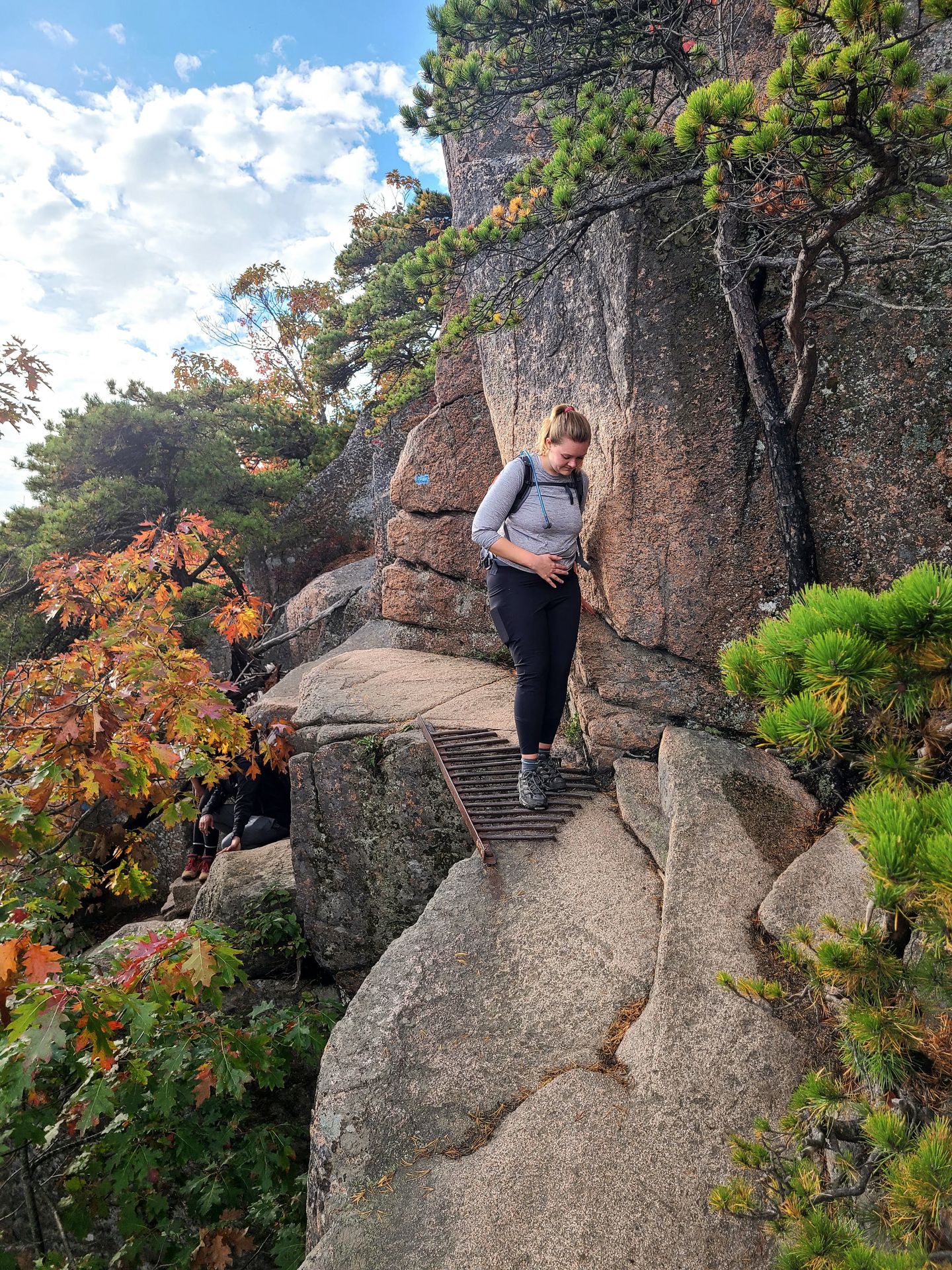 Lydia hiking across a metal bridge that is part of the Beehive trail.