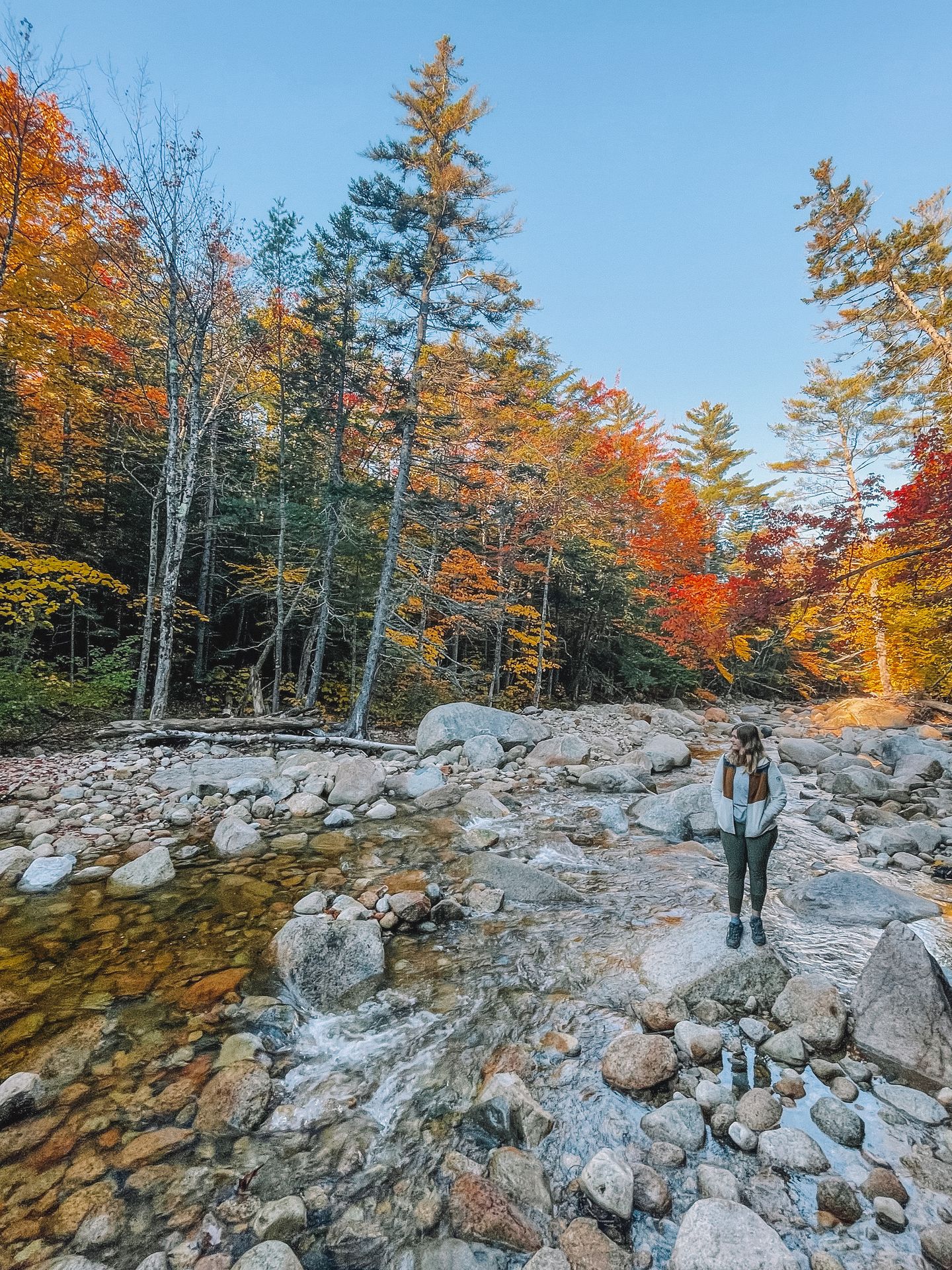 Lydia standing on small rocks next to a river.
