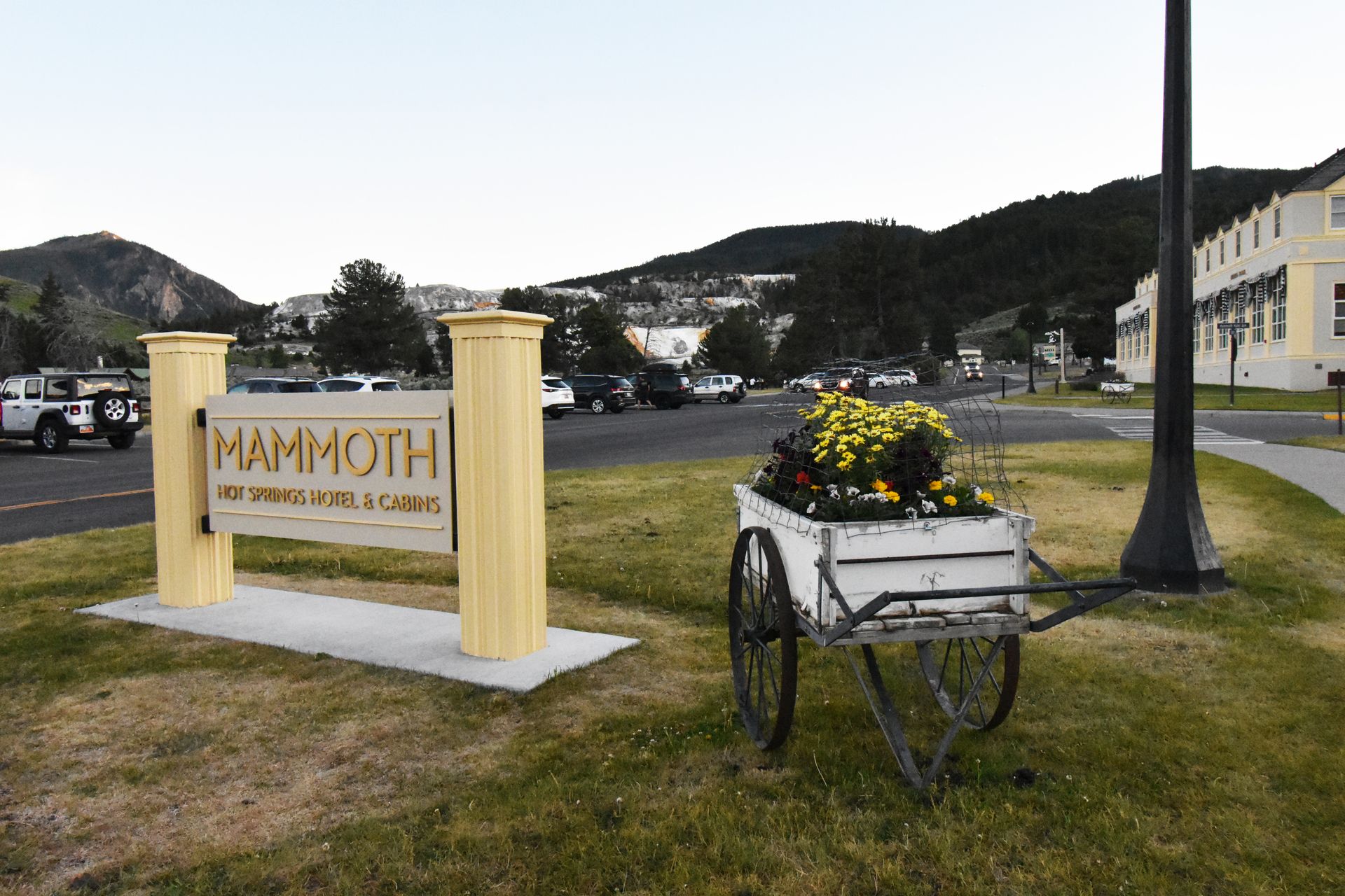 A sign and a wheel barrel with flowers in it ouside of the Mammoth Hot Springs Hotel