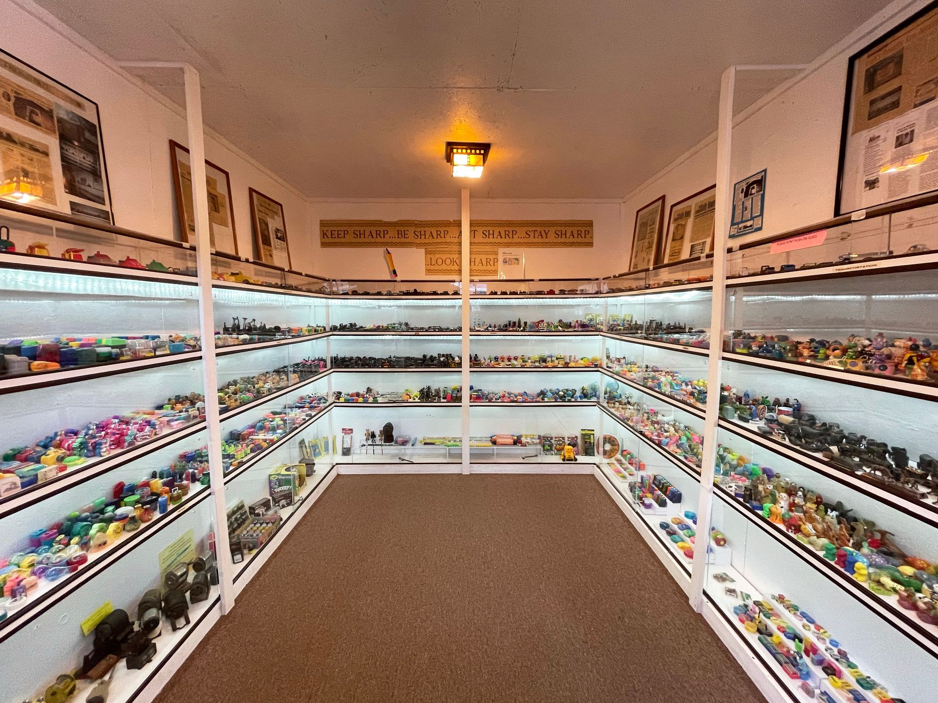 A small room with glass cases full of pencil sharpener's on every wall.