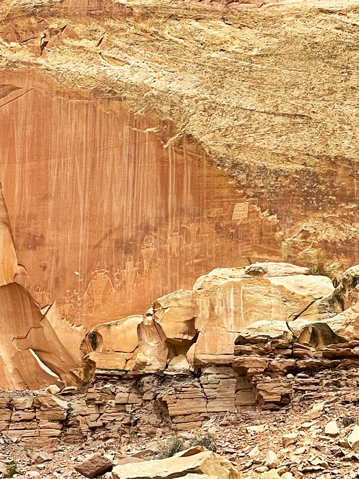 An orange rock wall with several petroglyph carvings.