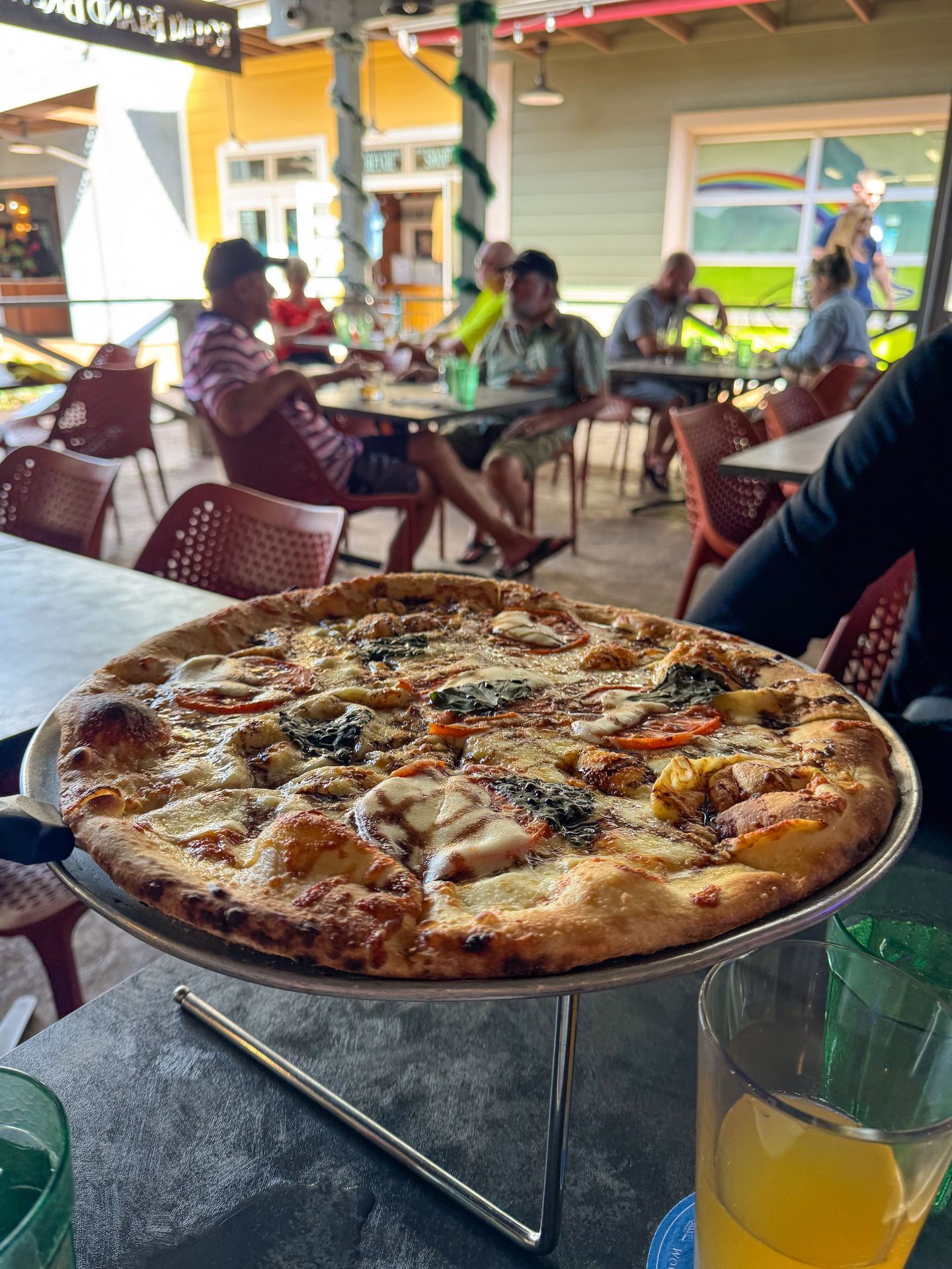 A pizza topped with some veggies on the outdoors patio of Kauai Island Brewing Company