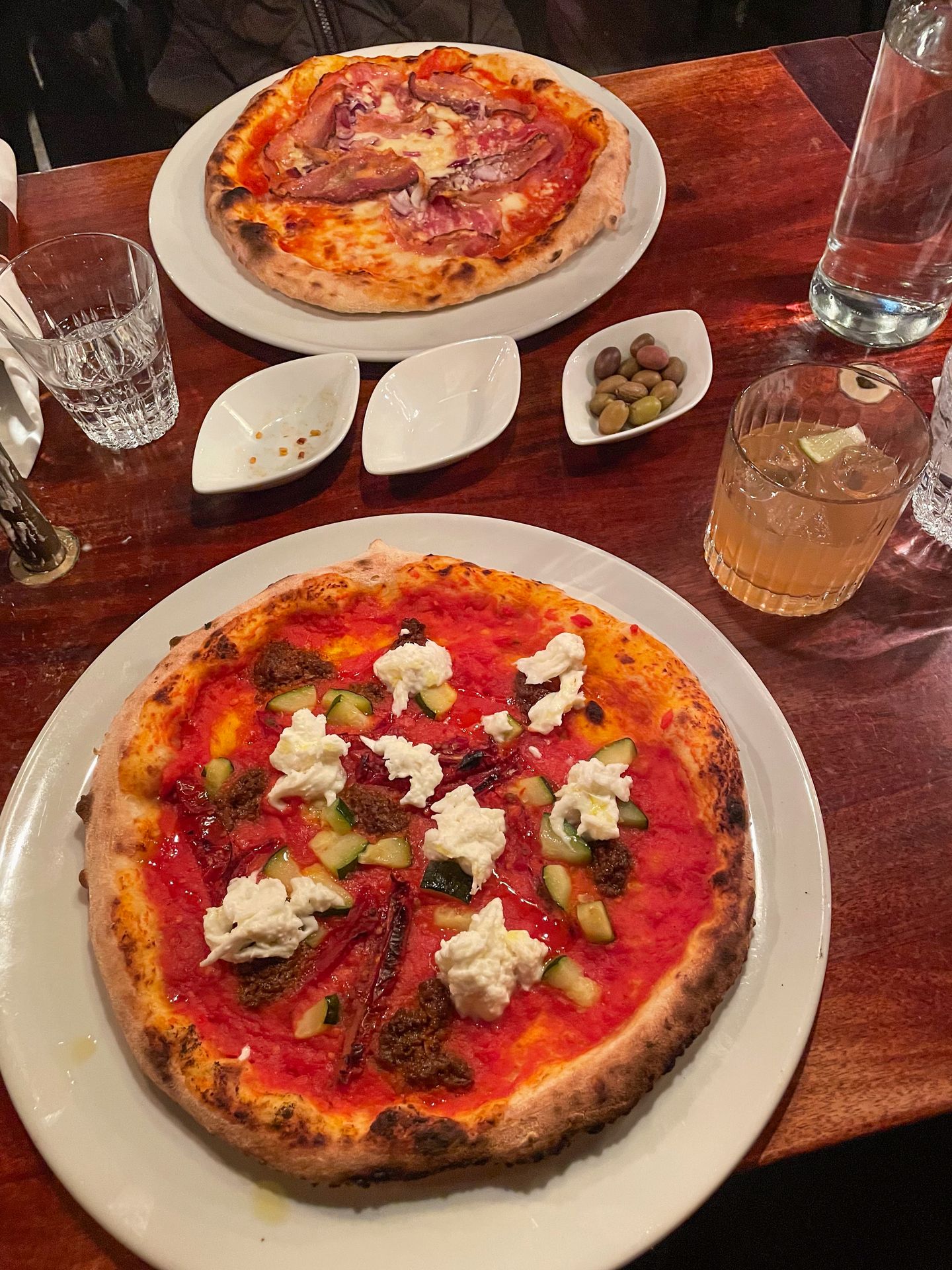 Two pizzas from Casa Inferno. One has sun-dried tomatoes and clumps of cheese