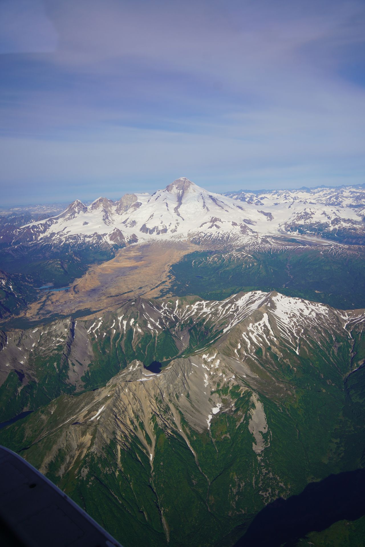 A view of snowy mountains and greenery seen from the flight to Katmai