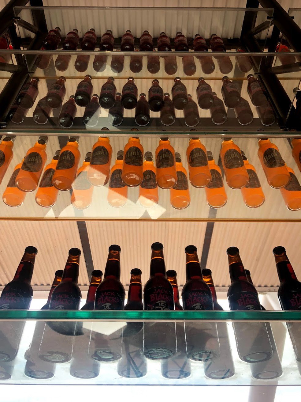 Looking up at glass shelves full of colorful soda bottles.
