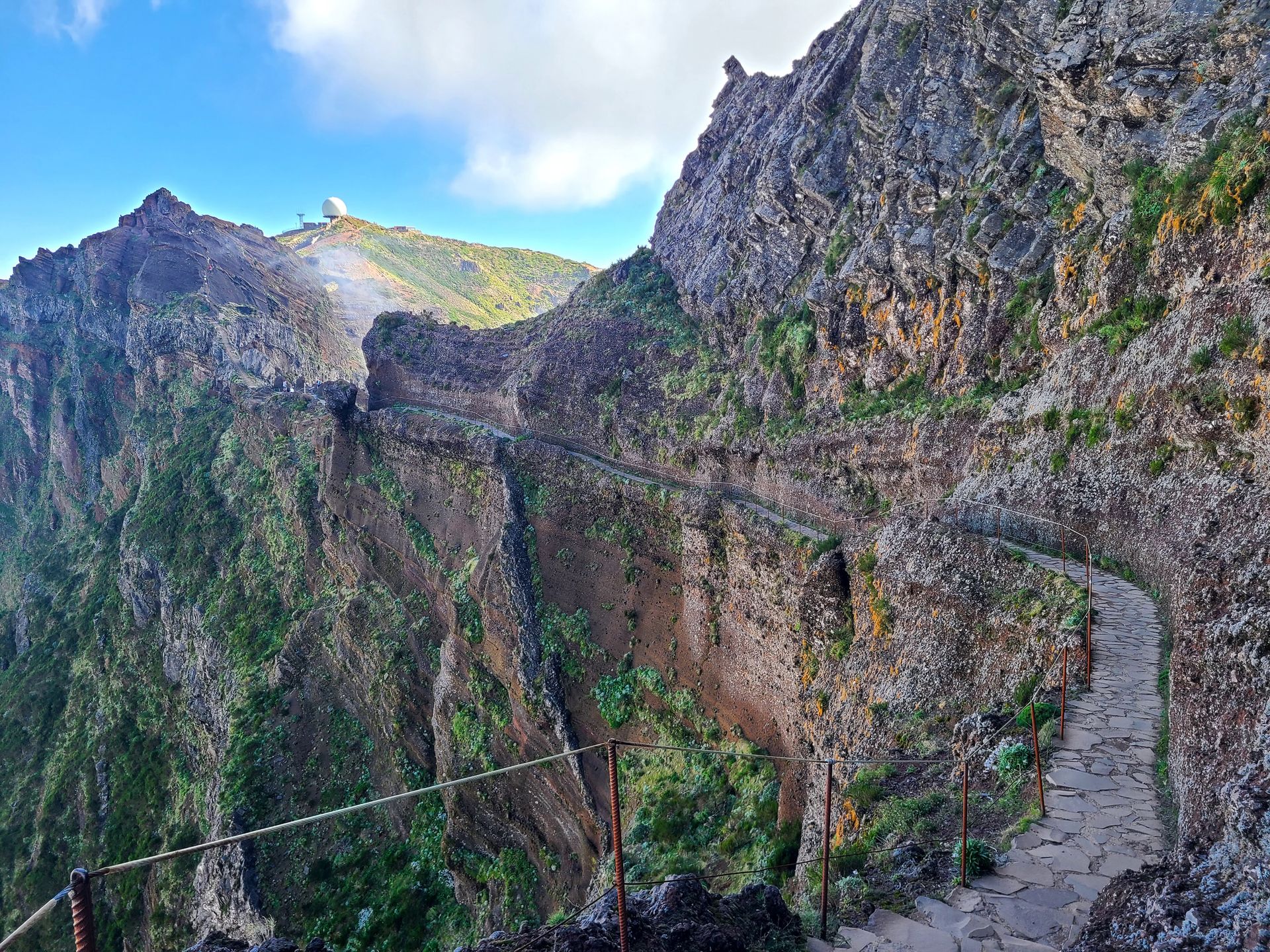 A trail with a railing following along the edge of a mountain