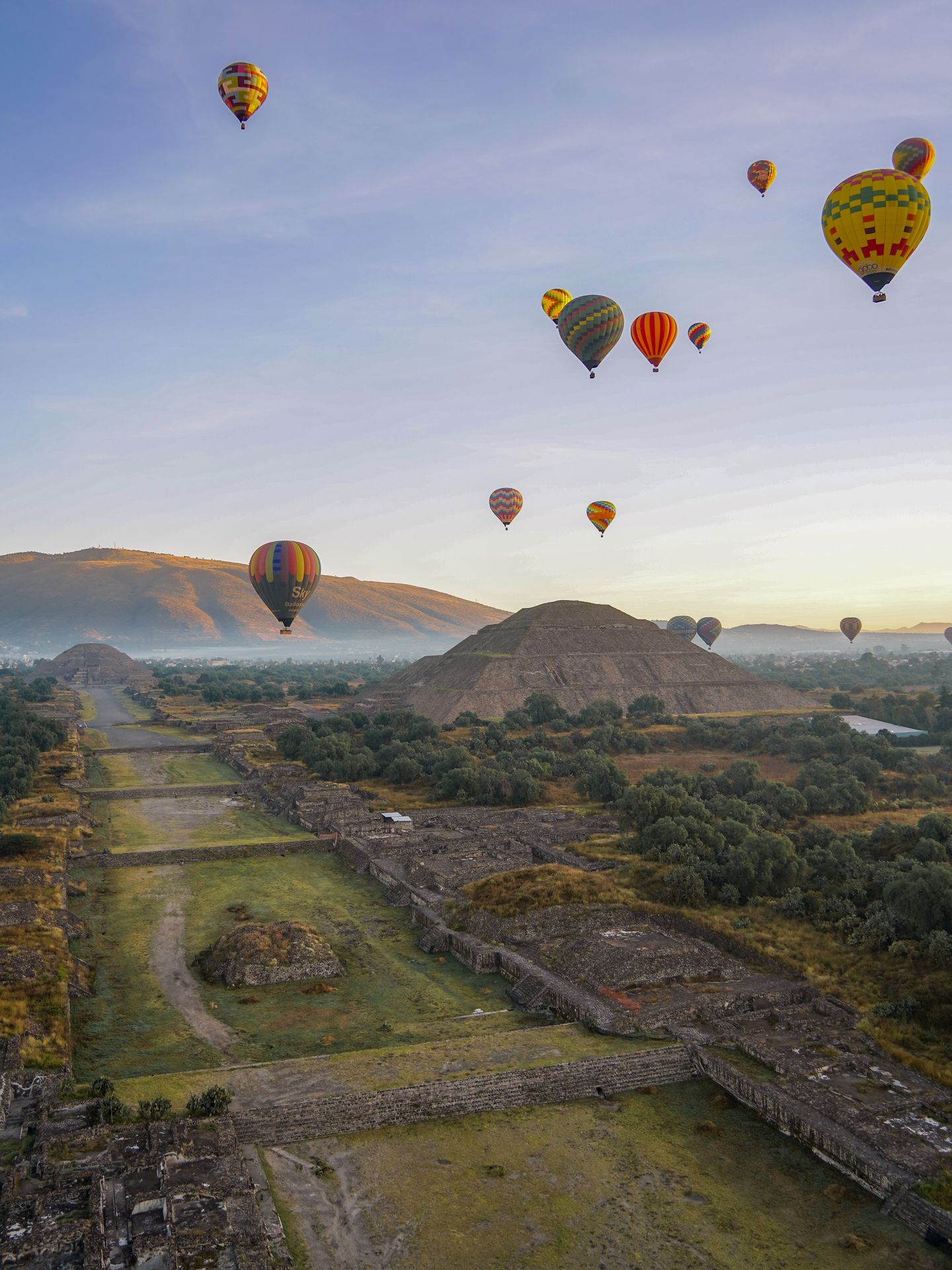 The view of sunrise over a pyramid with many balloons in the sky