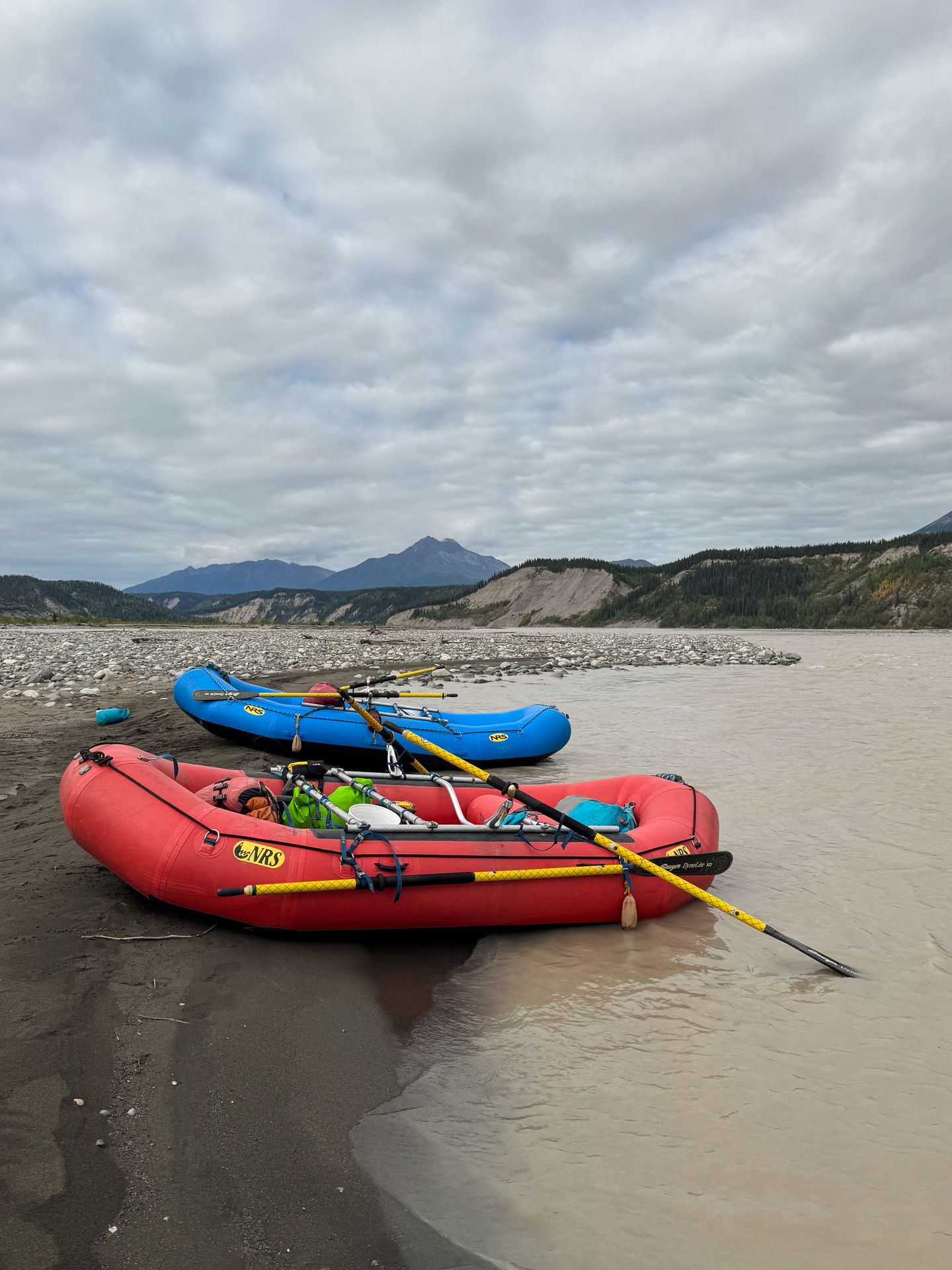 Two rafts on the shore of a wide river in Wrangell-St. Elias National Park