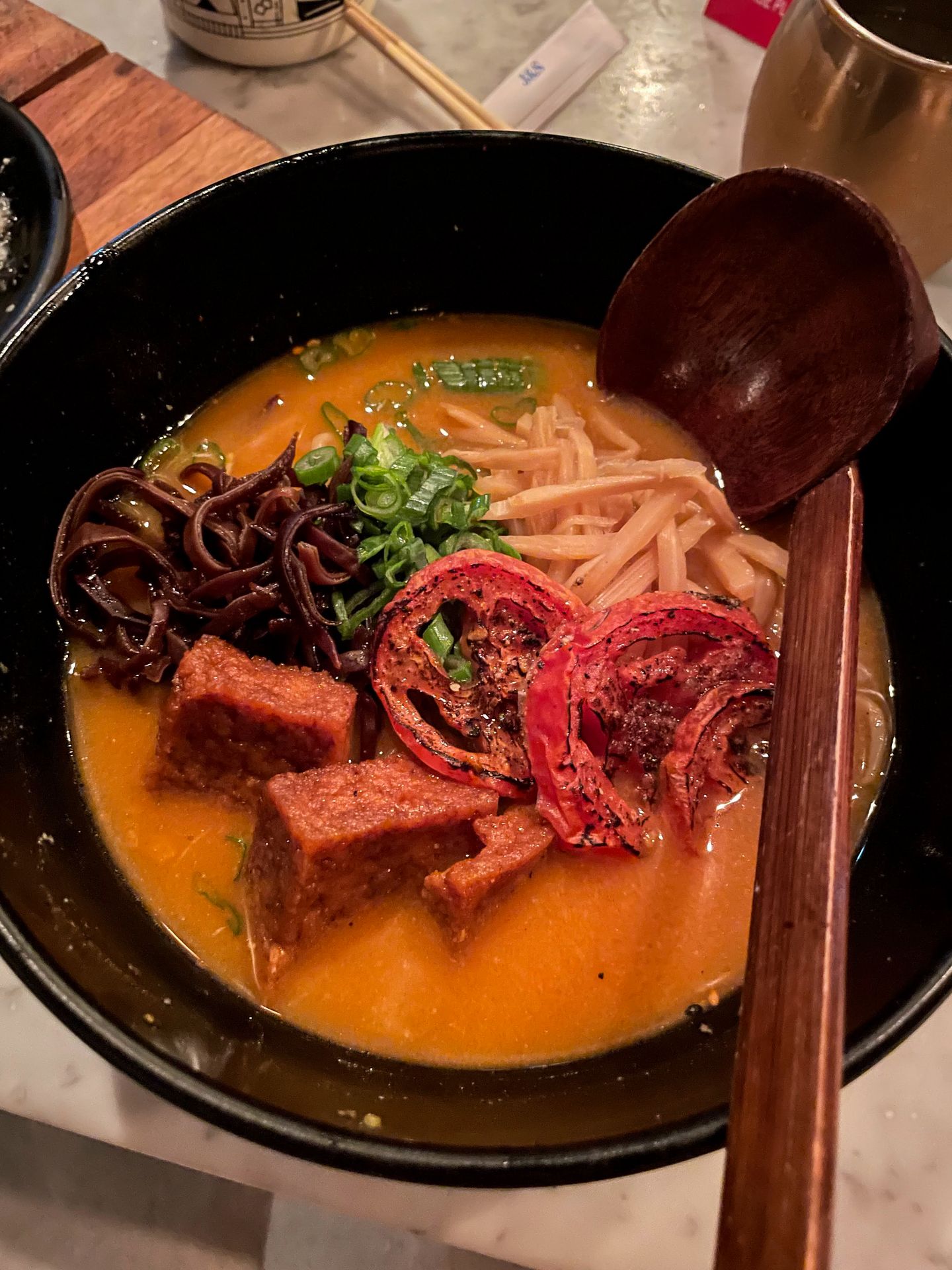 A bowl of ramen with noodles, tofu and veggies.