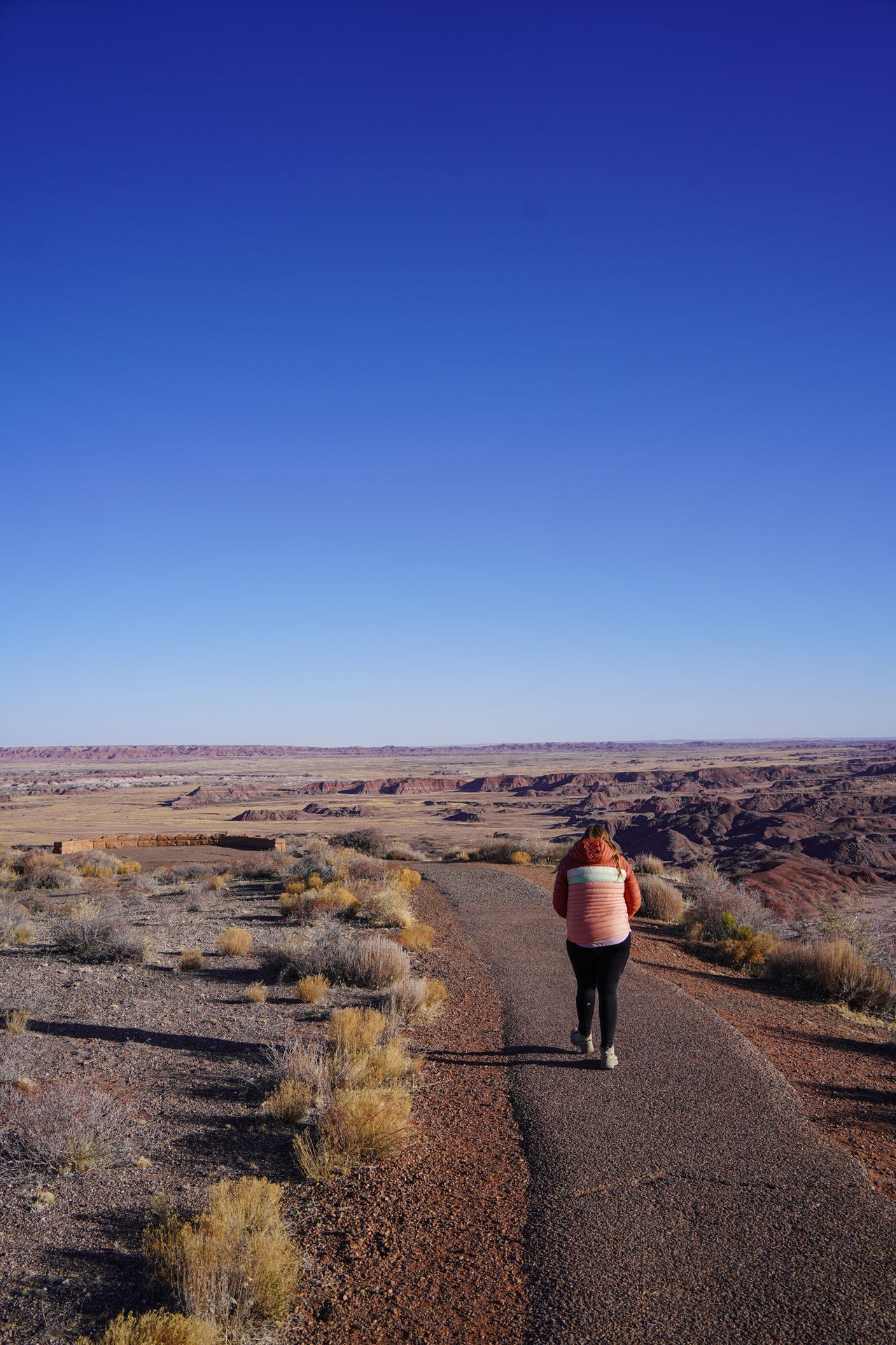 Lydia hiking on a paved trail with a view of red rocks in the distance
