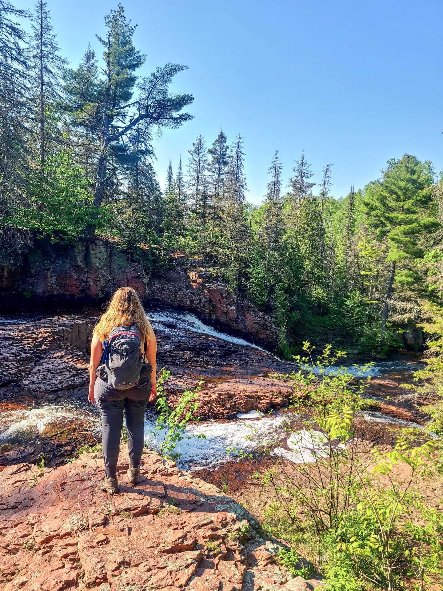 Lydia standing and looking out at a waterfall along the Split Rock Ridge Loop Trail.