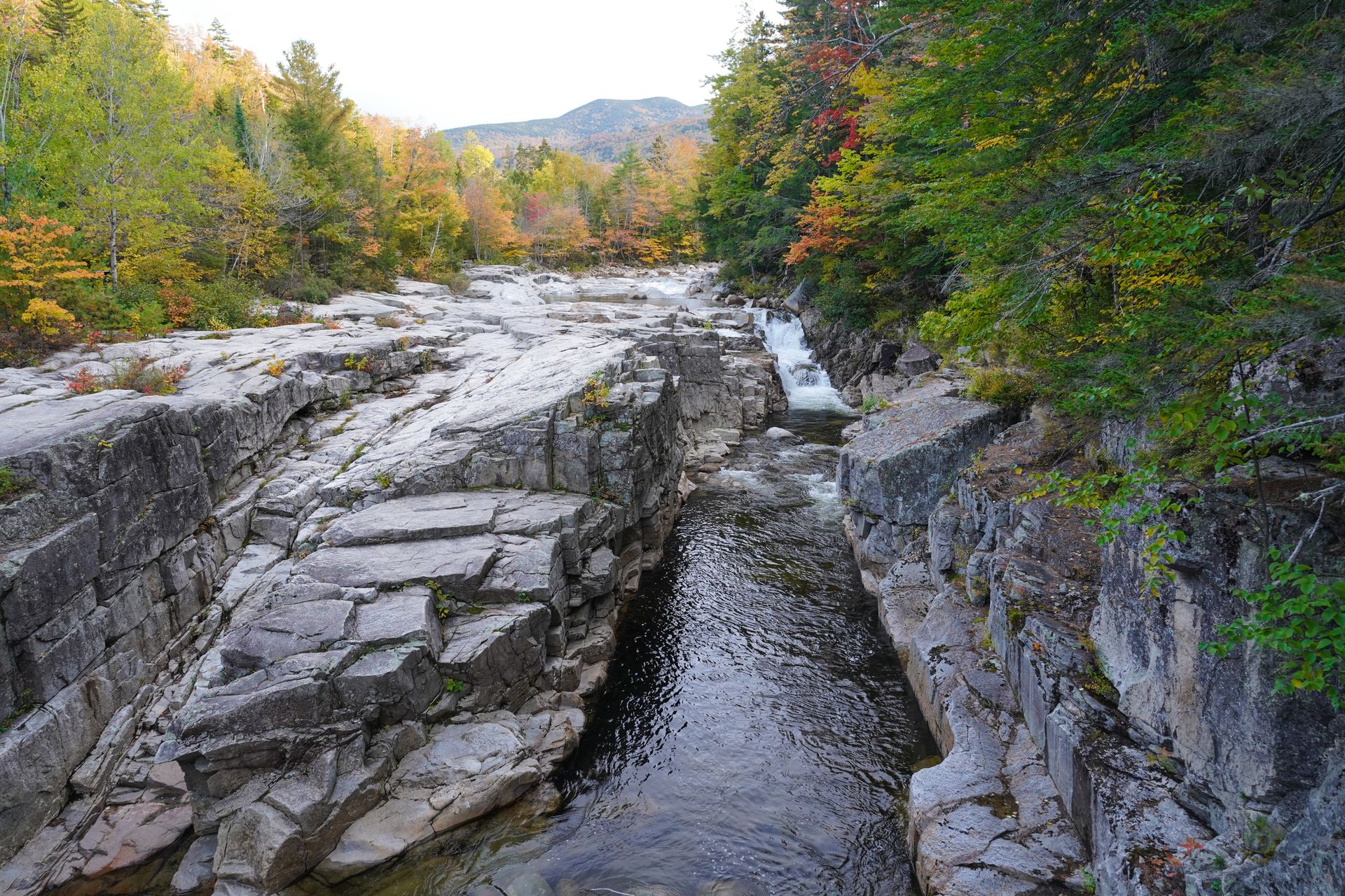 The view looking down at Rocky Gorge. There is a waterfall flowing down white rocks and fall foliage surrounding the gorge