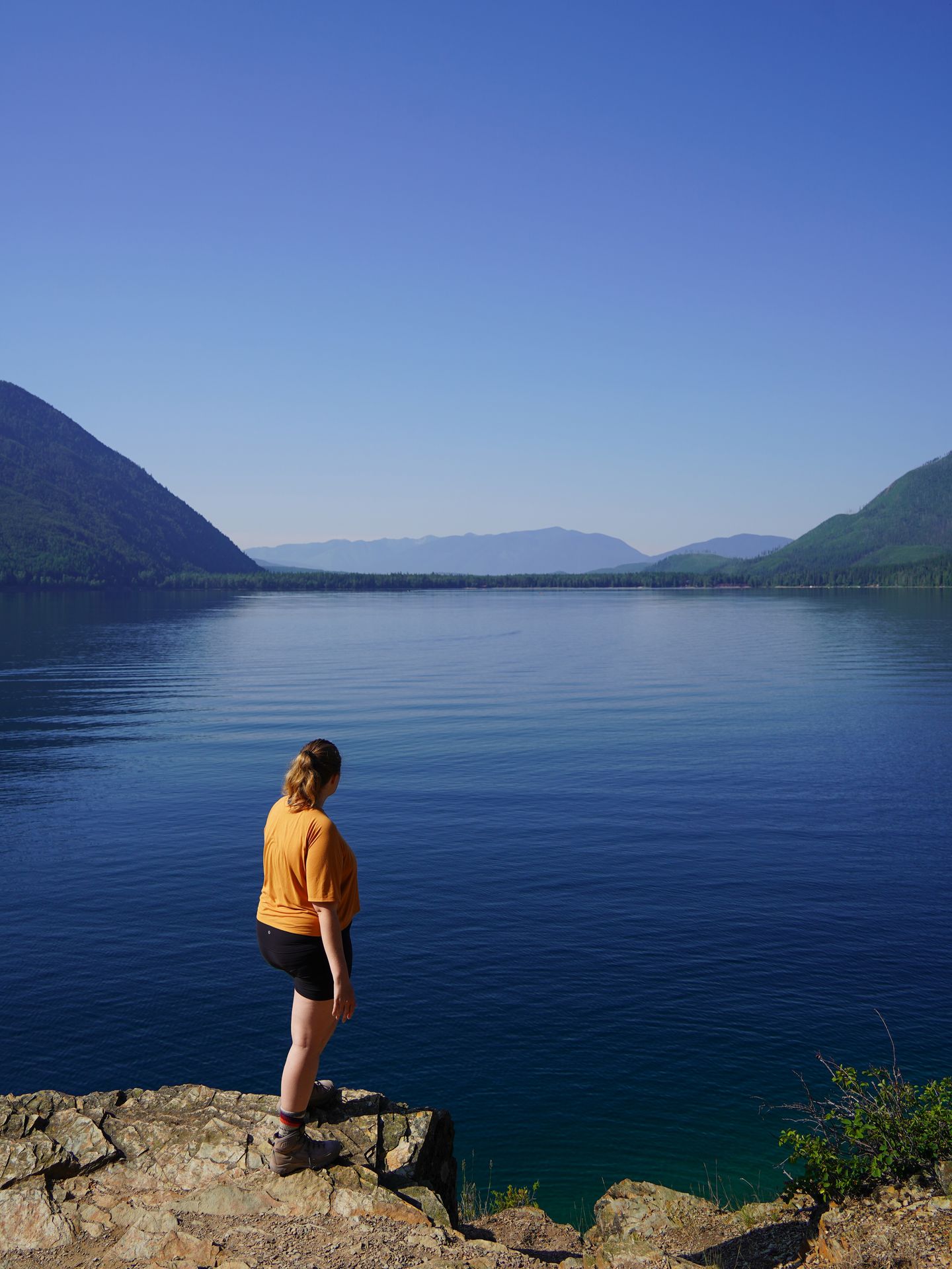 Lydia standing on a rocky ledge and looking out at Lake McDonald