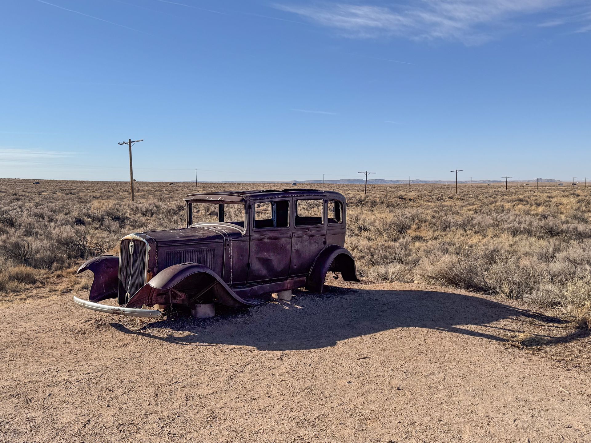 A historic car without wheels and a path of telephone pools marking the place where Route 66 was