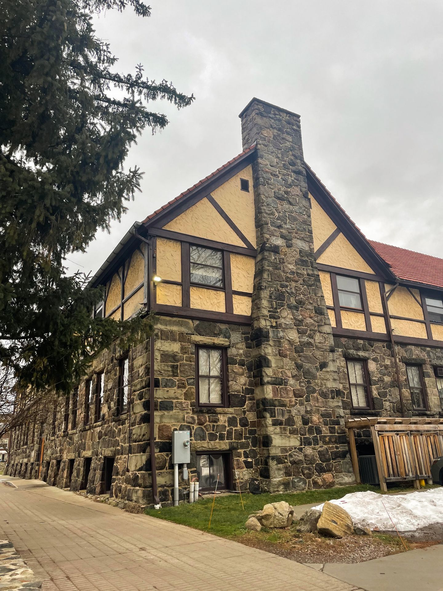 A buiding made of stones that is painted yellow at the top. A large chimney is on the edge of the building.