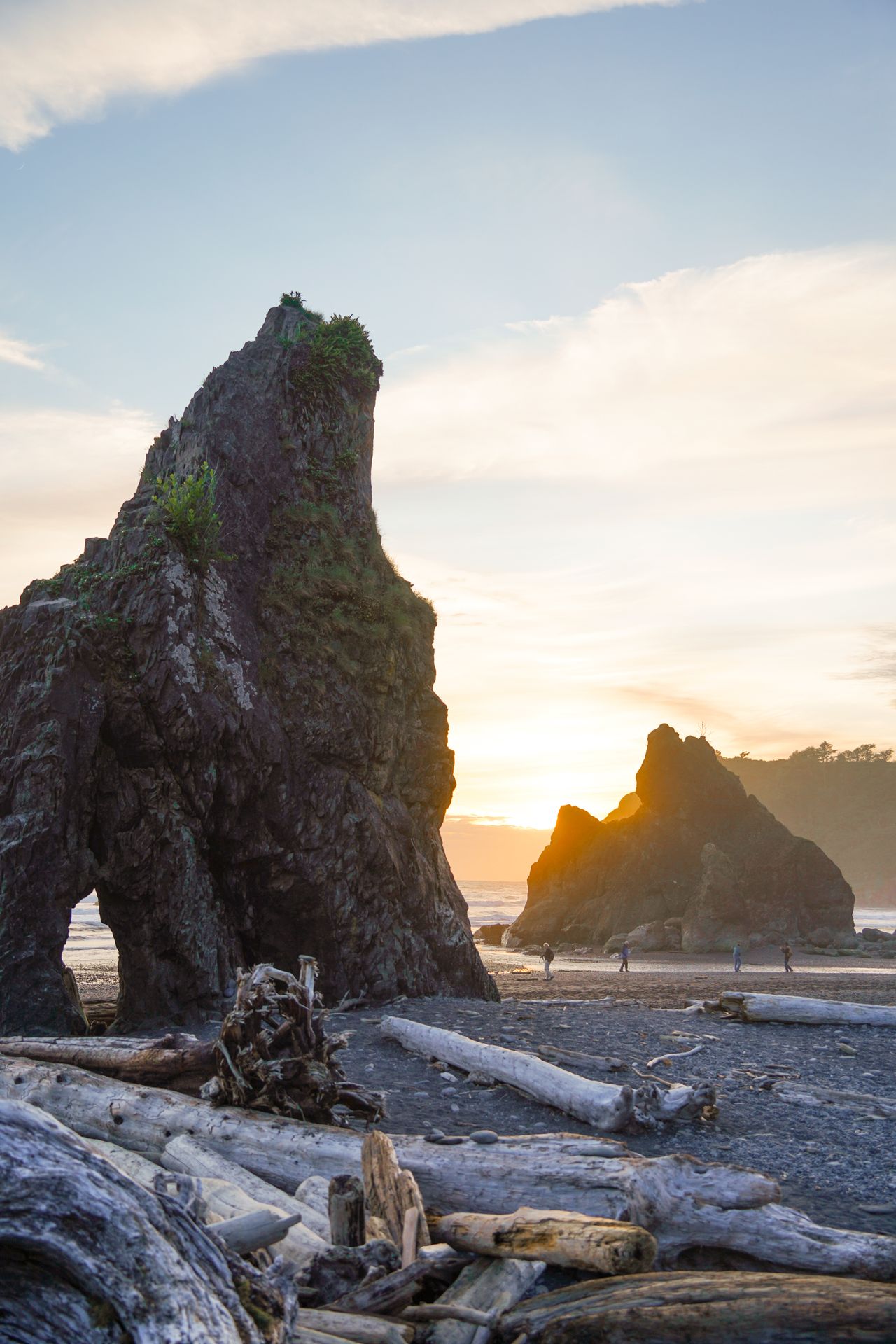 Rock formations and driftwood logs on Ruby Beach at sunset