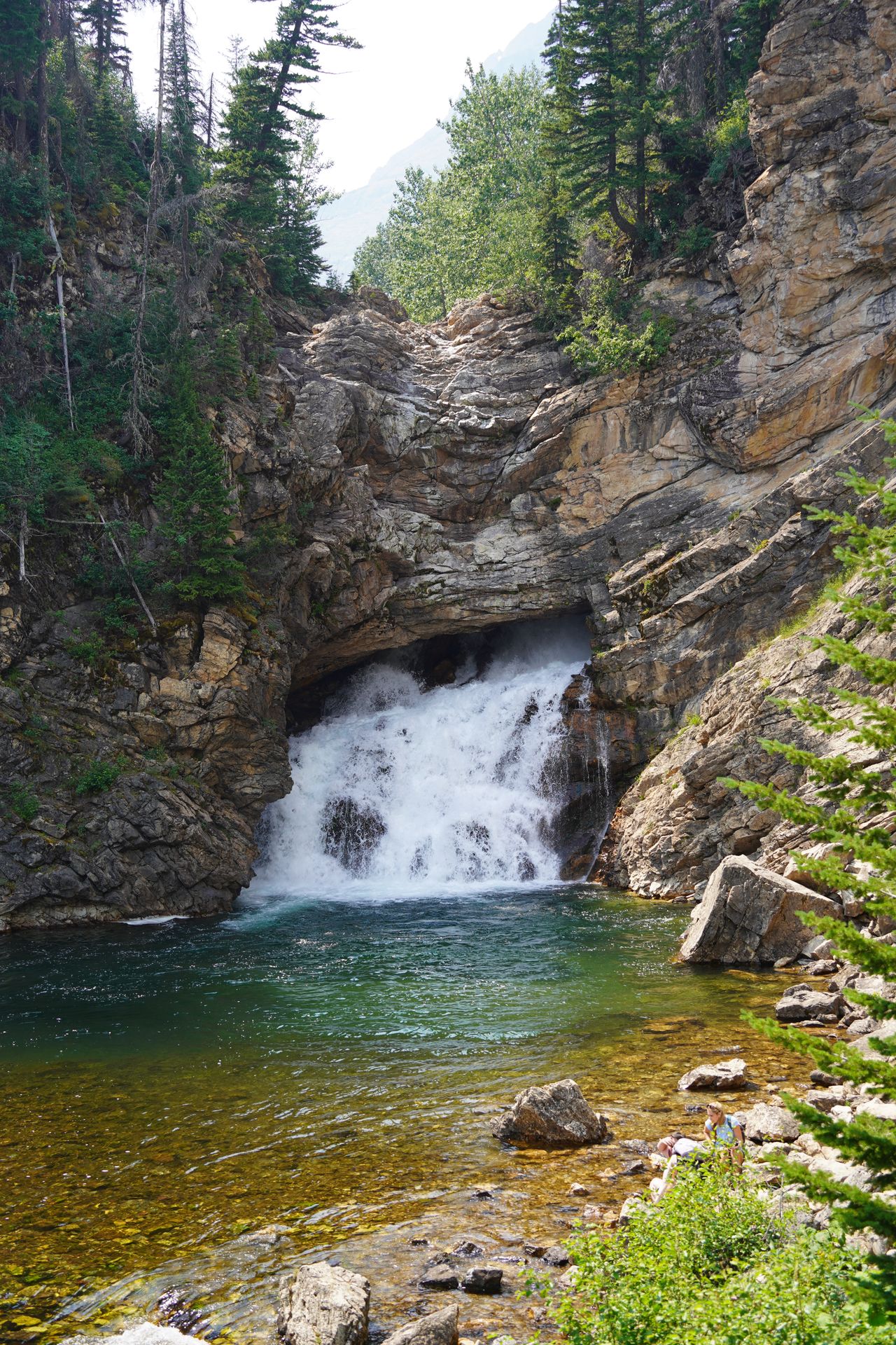 A waterfall that looks to come out from the middle of a large rock face.