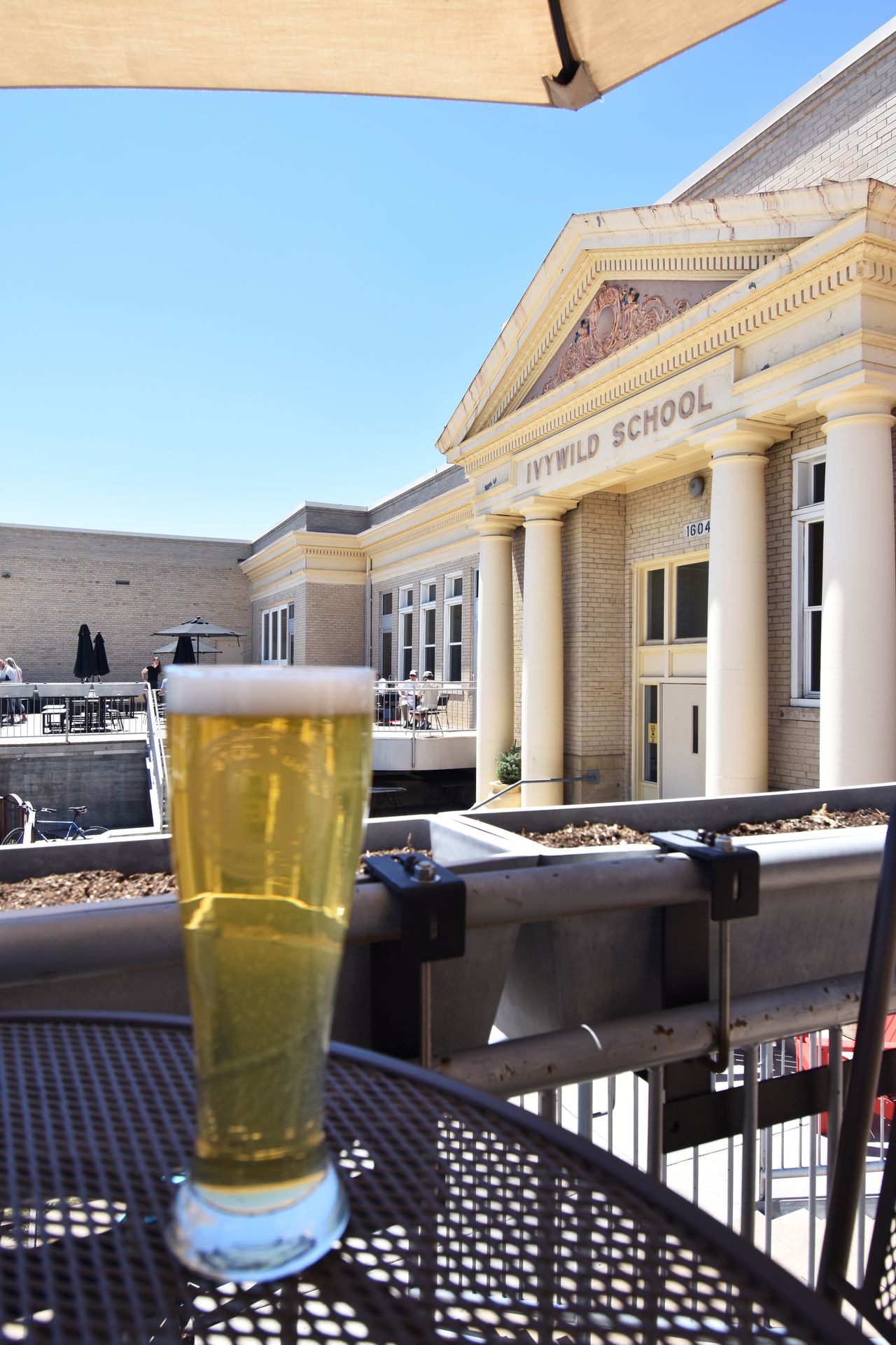 A tall glass of beer on a table in the patio of Ivywild School