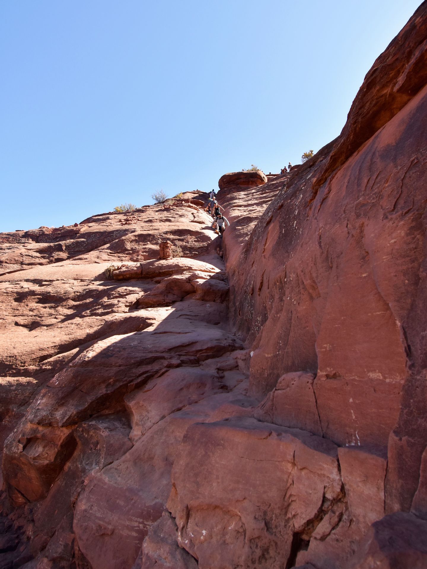 Looking up at a rock scramble on the Cathedral Rock trail. You climb up an orange rock face and it requires some big steps.