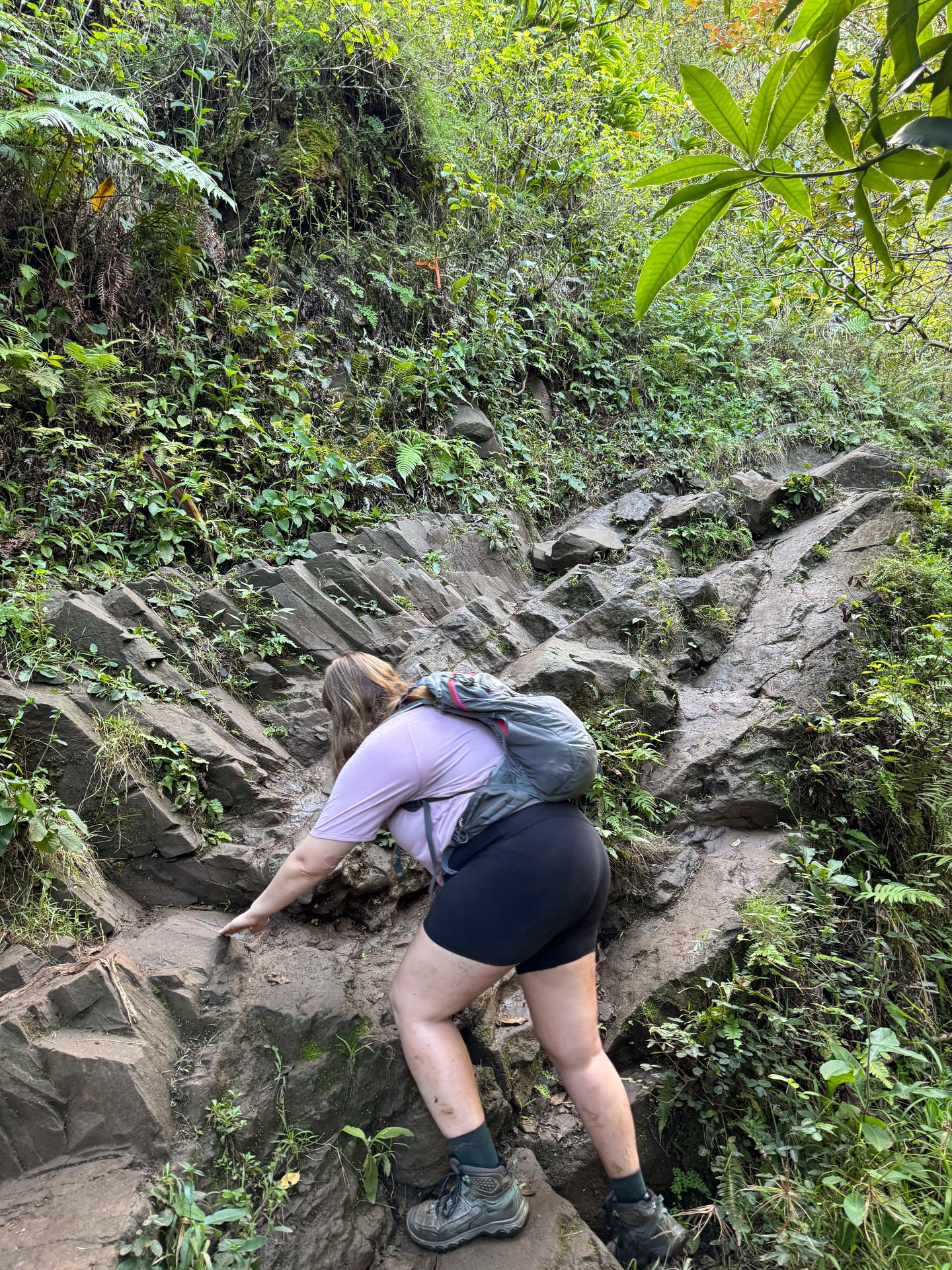Lydia scrambling up muddy rocks on the way to Hanakapi'ai Falls
