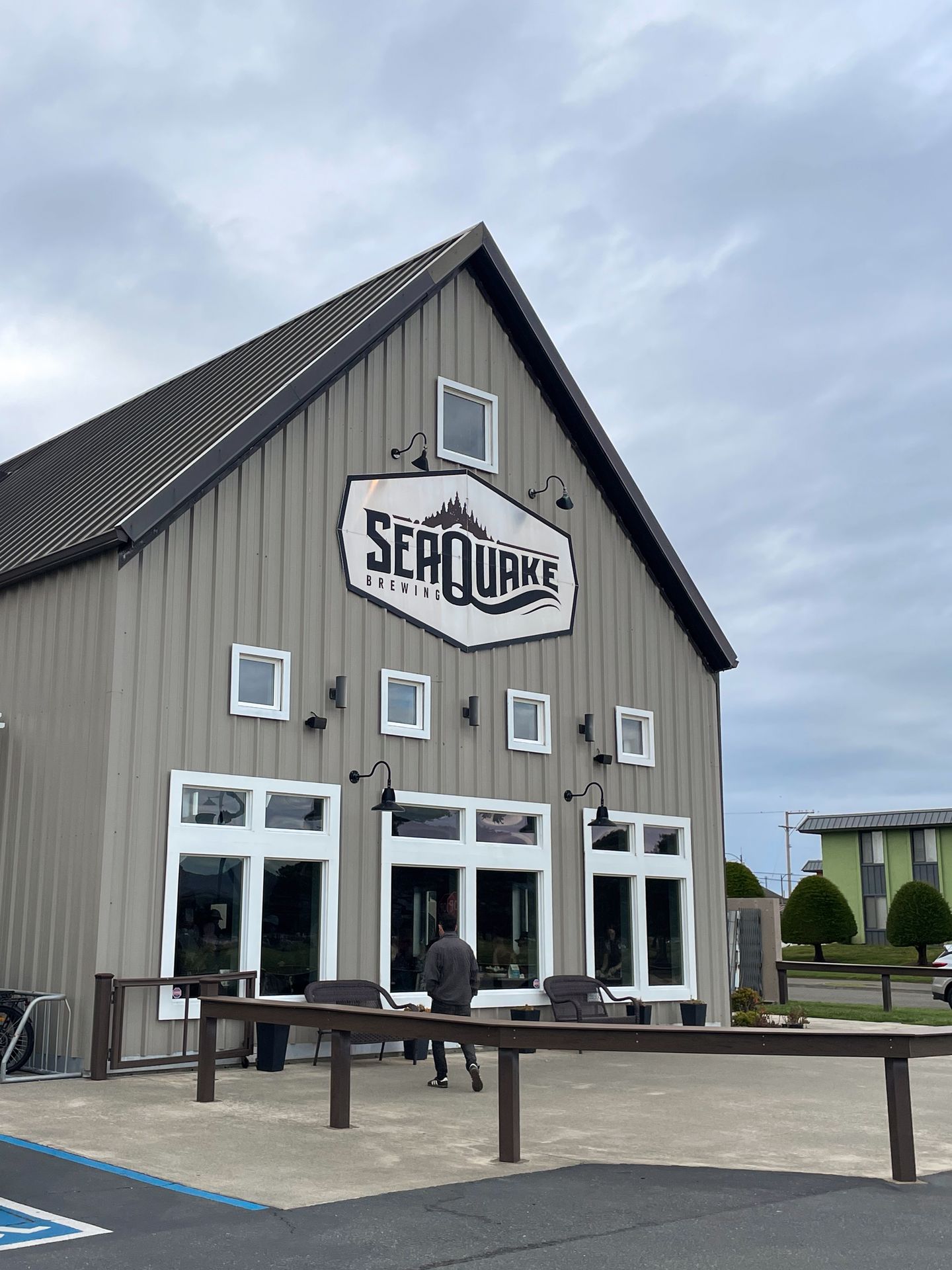 The exterior of Seaquake Brewing, which is a gray building with a white sign with black letters