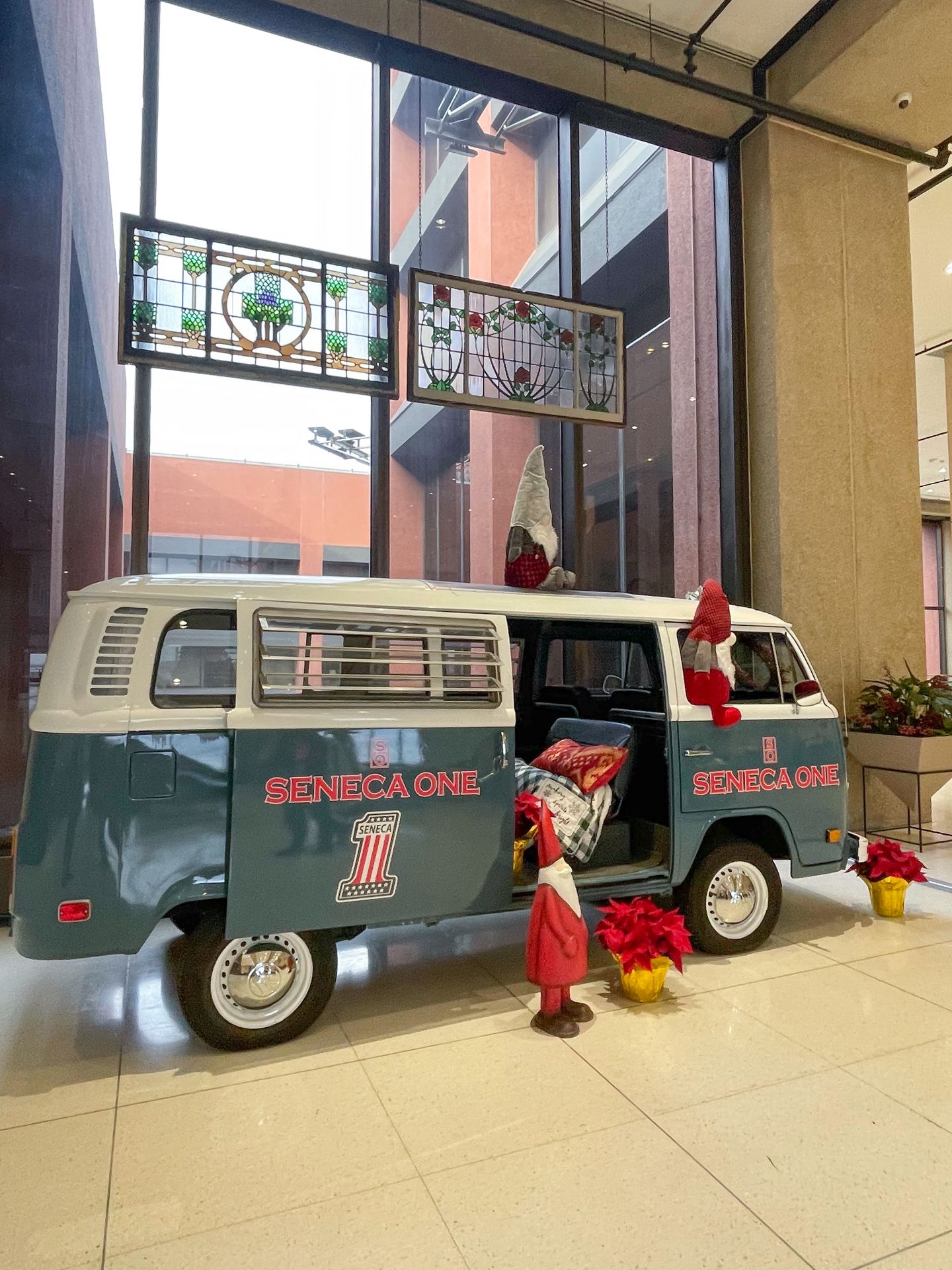 A two toned van that is blue on the bottom and white on the top that reads 'Seneca One.' There is Christmas decor inside and around the van, including small Santa Clause statues.