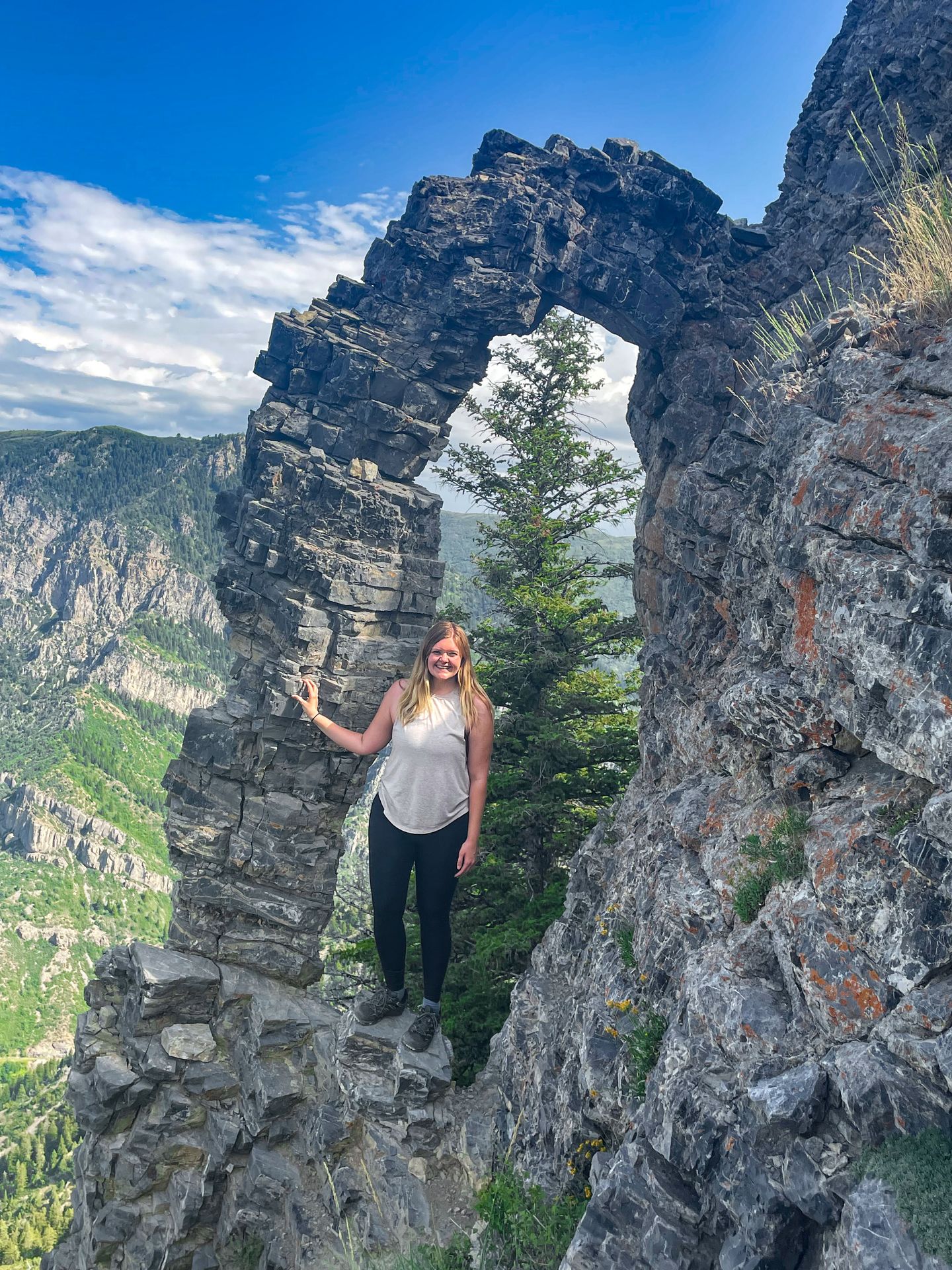Lydia standing in front of a stone arch on a hike near Salt Lake City